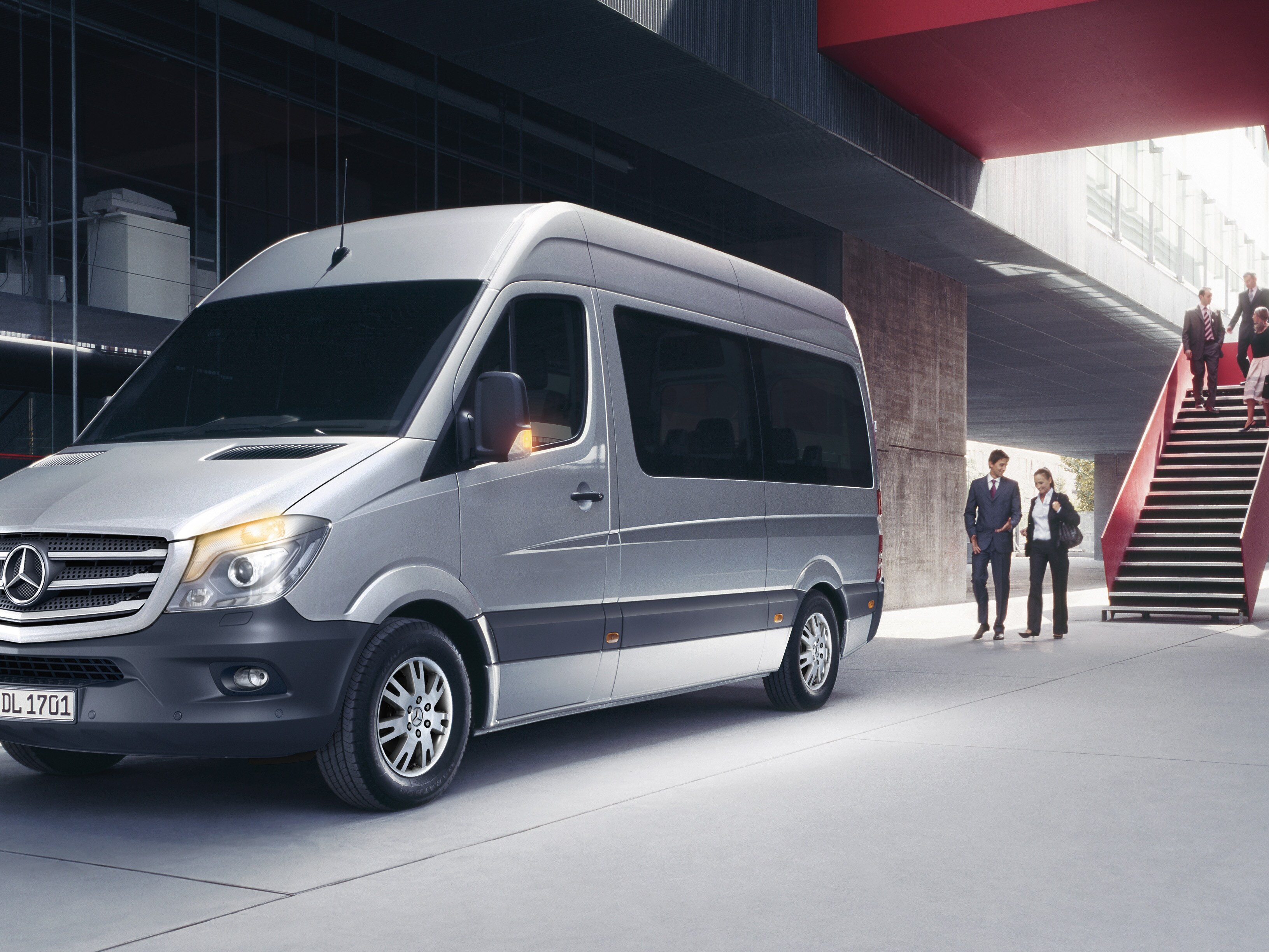 Groep jonge vrienden stapt in een zwarte Mercedes-Benz T-Klasse geparkeerd voor een modern gebouw, genietend van een zonnige dag.