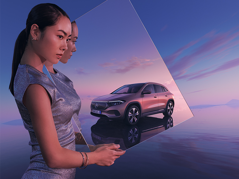 Mercedes-Benz öffentliches Laden Eine Person hält einen Spiegel indem sich ein Mercedes-Benz EV spiegelt