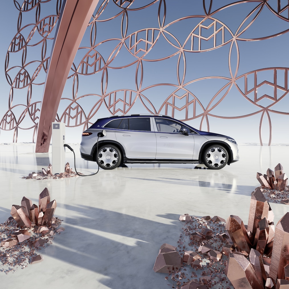 Vue latérale de la Mercedes-Maybach EQS SUV à la borne de recharge, avec le logo de la marque Maybach en arrière-plan.