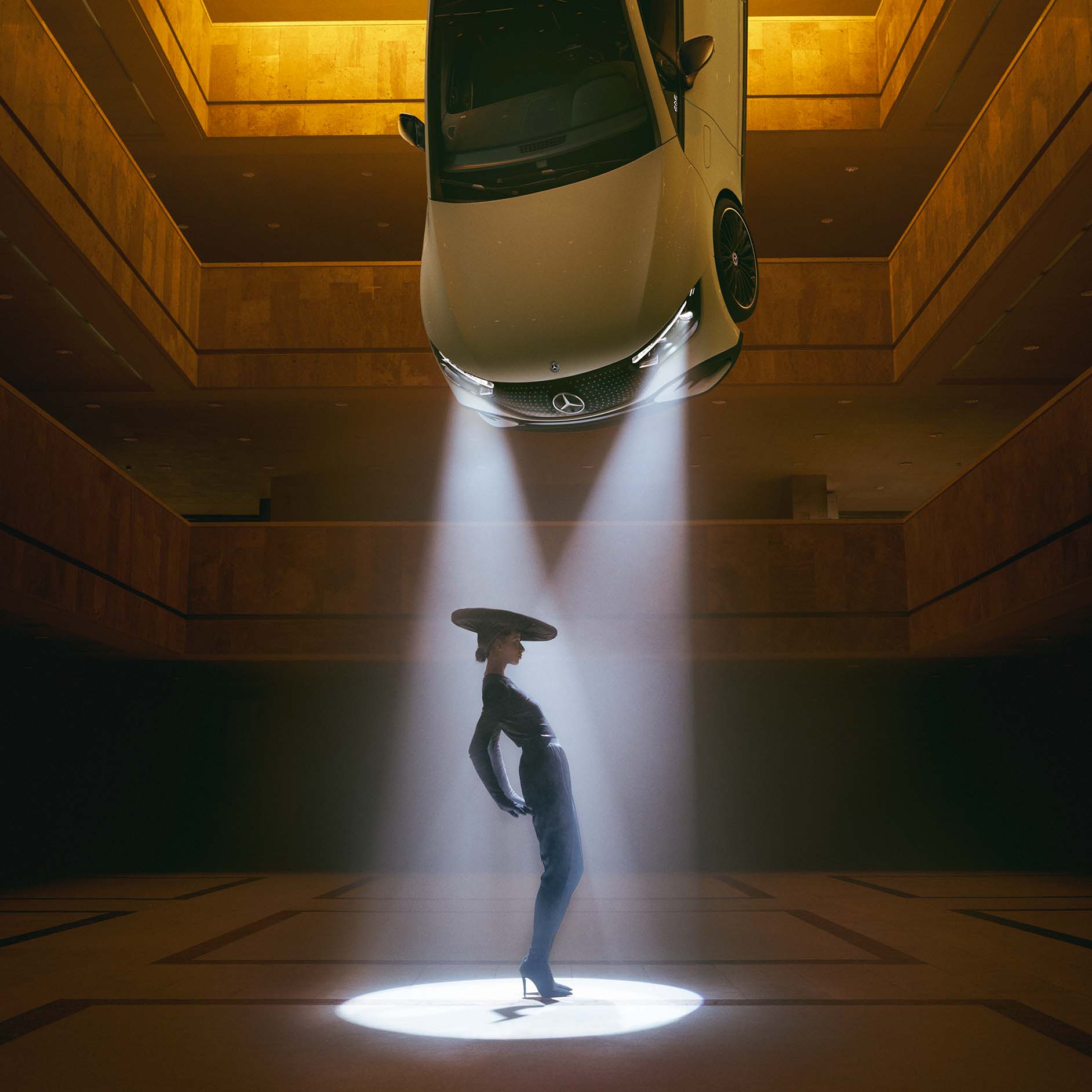 DIGITAL LIGHT Lichttechnologie von Mercedes-Benz Ein dunkler Raum, an dessen Decke Scheinwerfer hängen, in deren Lichtkegel eine Frau steht.