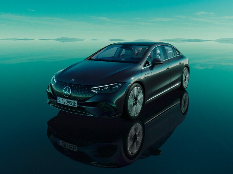 La Mercedes EQE entièrement électrique debout dans son univers EQ vert avec une surface de plancher réfléchissante.