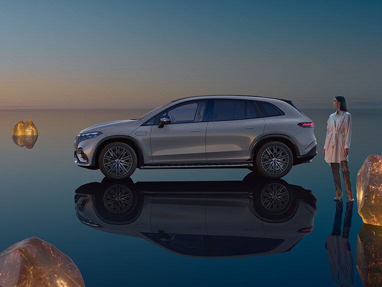 La Mercedes EQS SUV entièrement électrique debout dans son univers EQS SUV avec une surface de plancher réfléchissante.