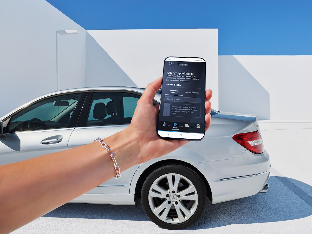 Eine Frau meldet online einen Fahrzeug-Schaden über ihr Smartphone.