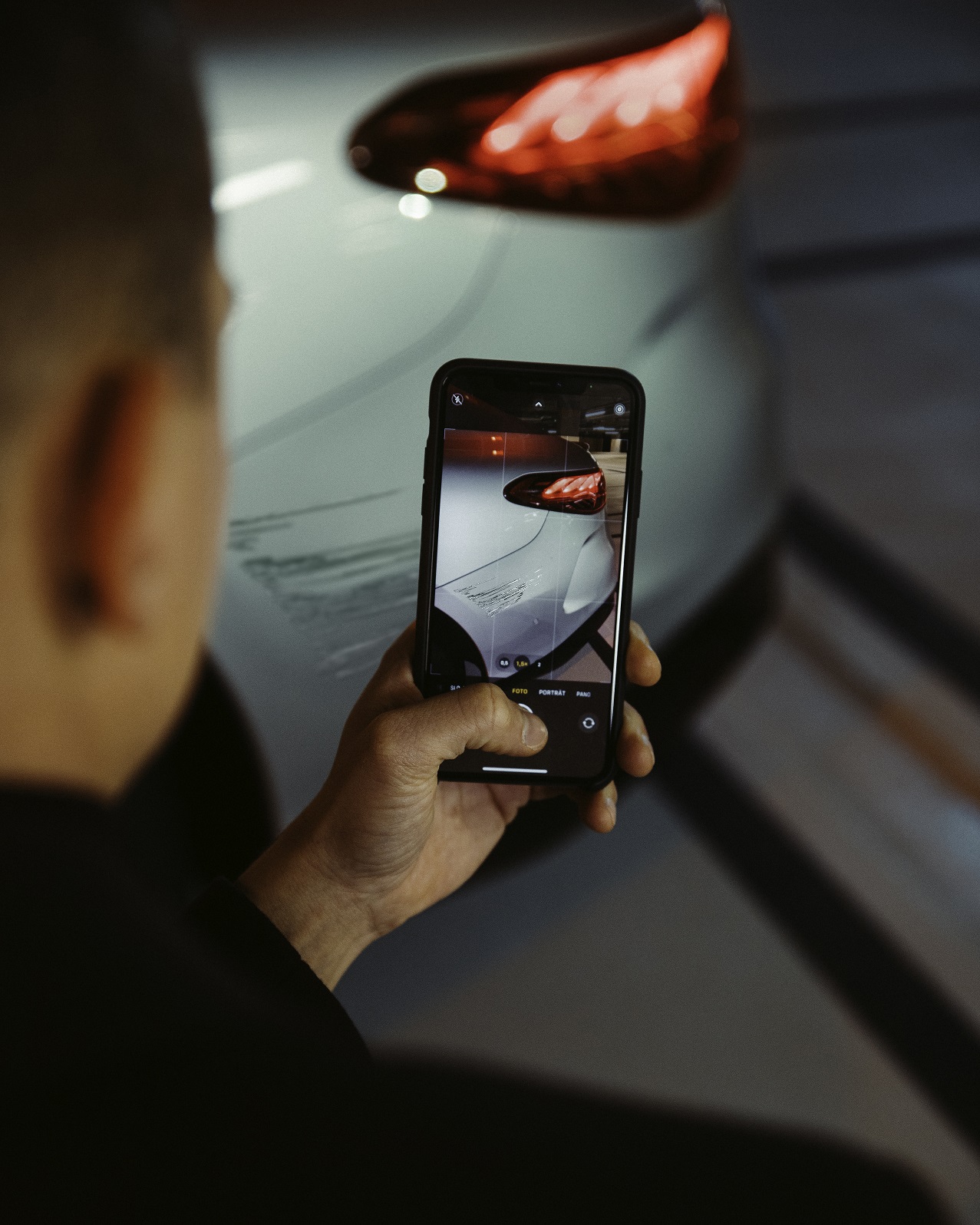 Assistance en cas de sinistre | Mercedes-Benz Avec un smartphone, un homme photographie les dégâts sur l'aile arrière de sa Mercedes.