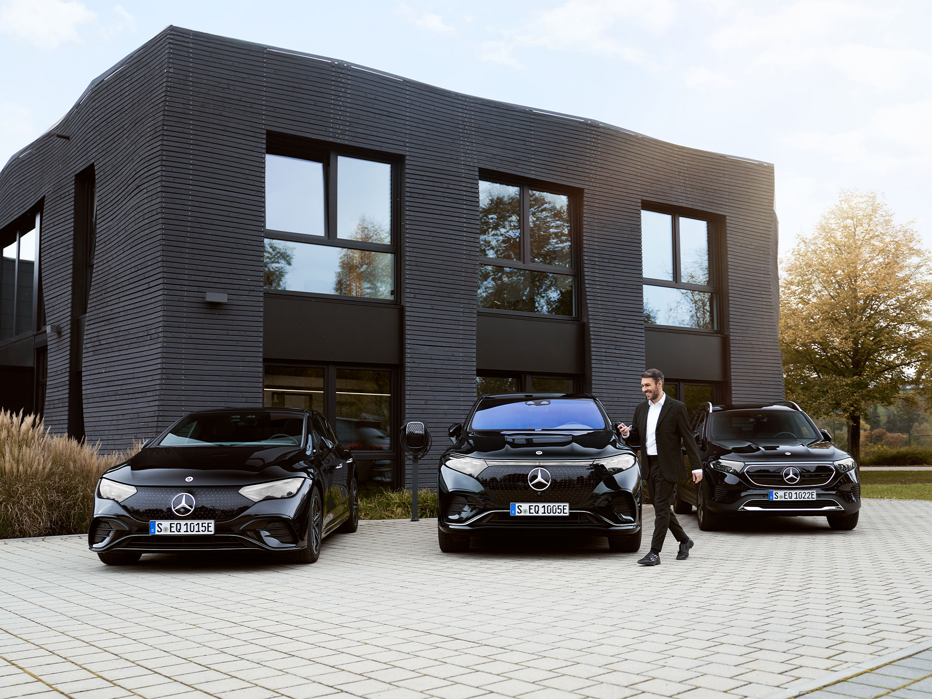 Recharge sur le lieu de travail | Recharge | Mercedes-Benz Trois véhicules électriques Mercedes-Benz devant un immeuble de bureaux.