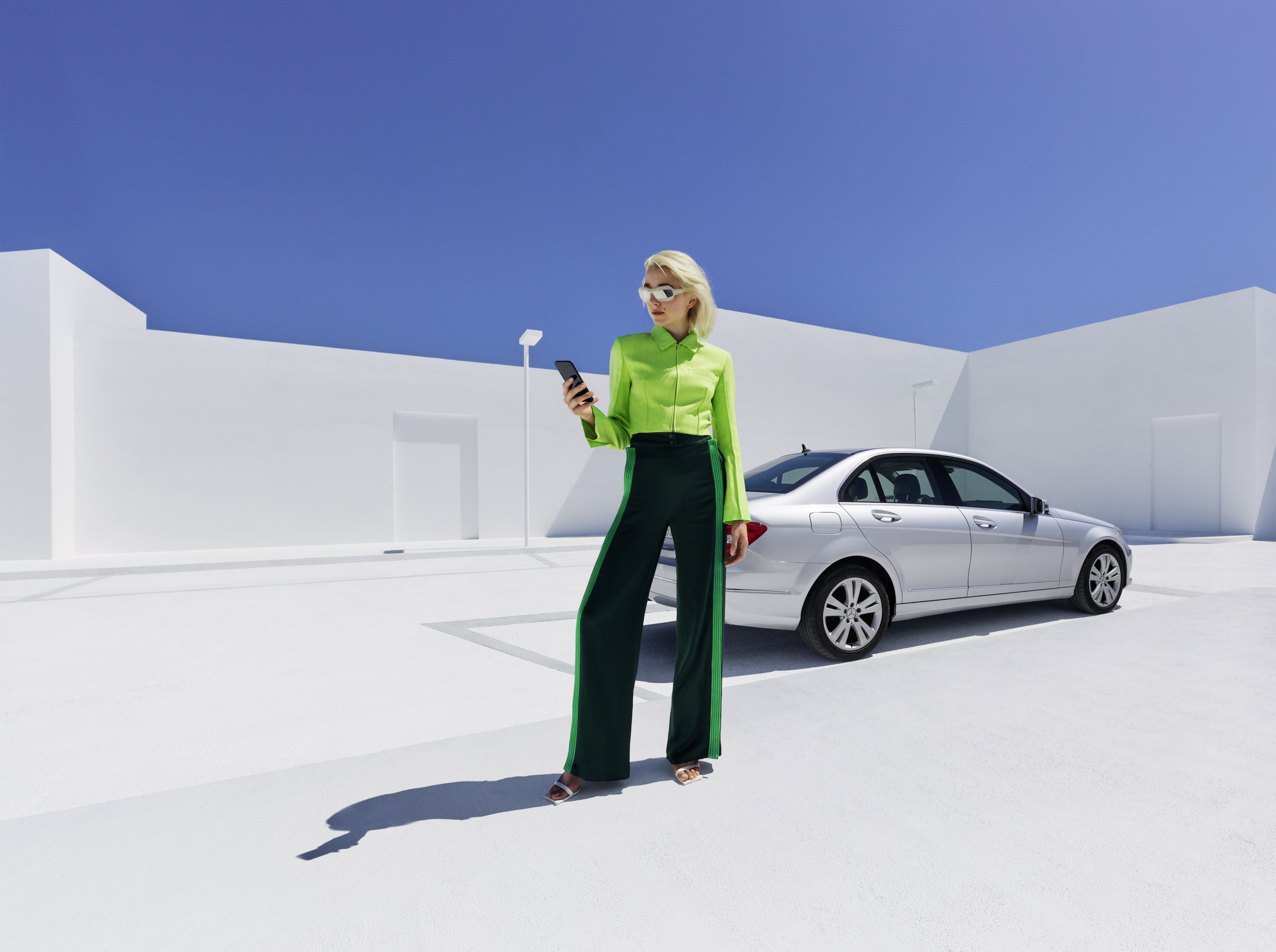 Mercedes me Adapter Une femme se tient devant sa Mercedes-Benz et consulte son smartphone.