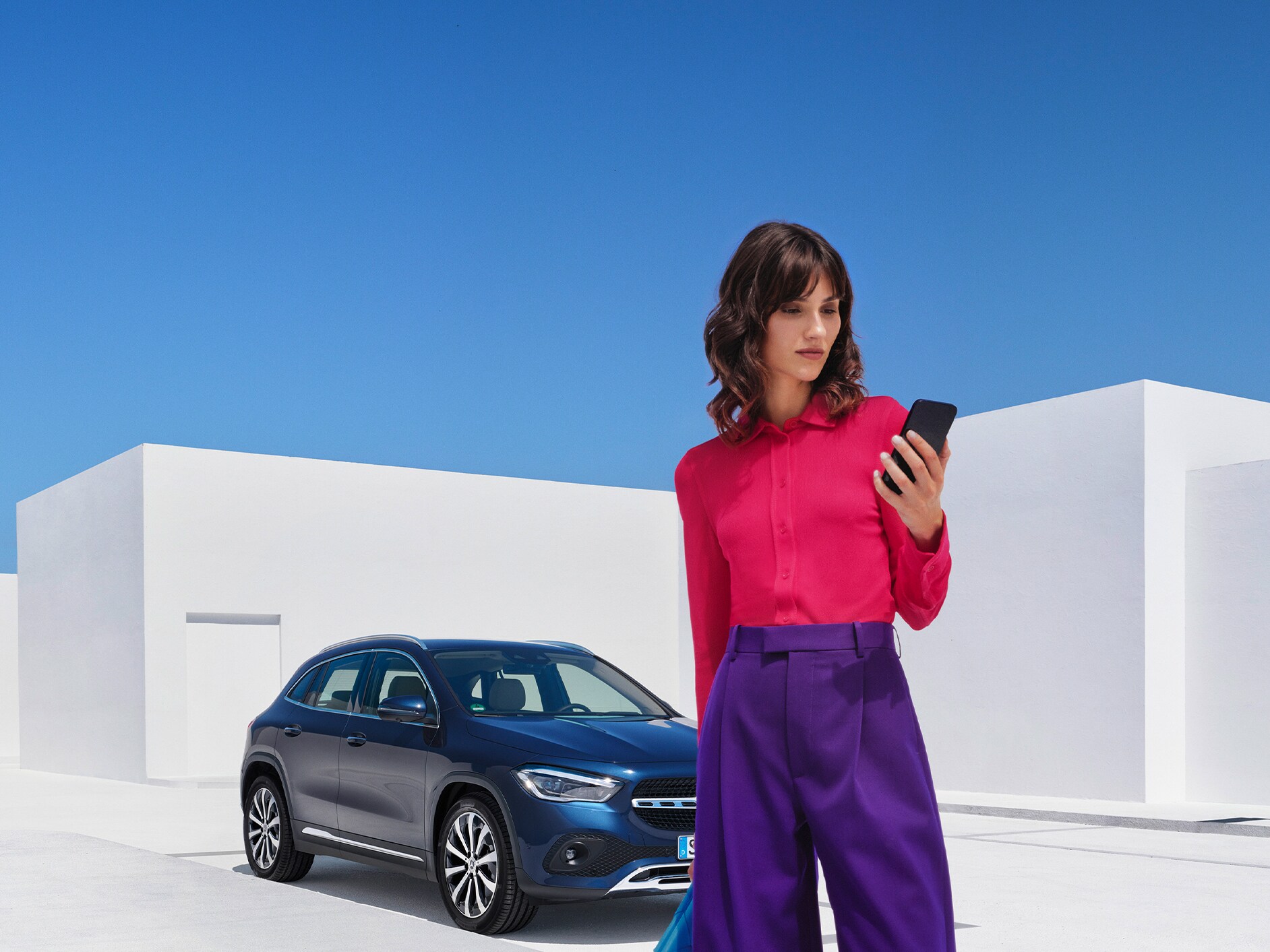 Eine Frau stellt per Mercedes-Benz App auf ihrem Smartphone eine Verbindung mit ihrem Mercedes-Benz her.
