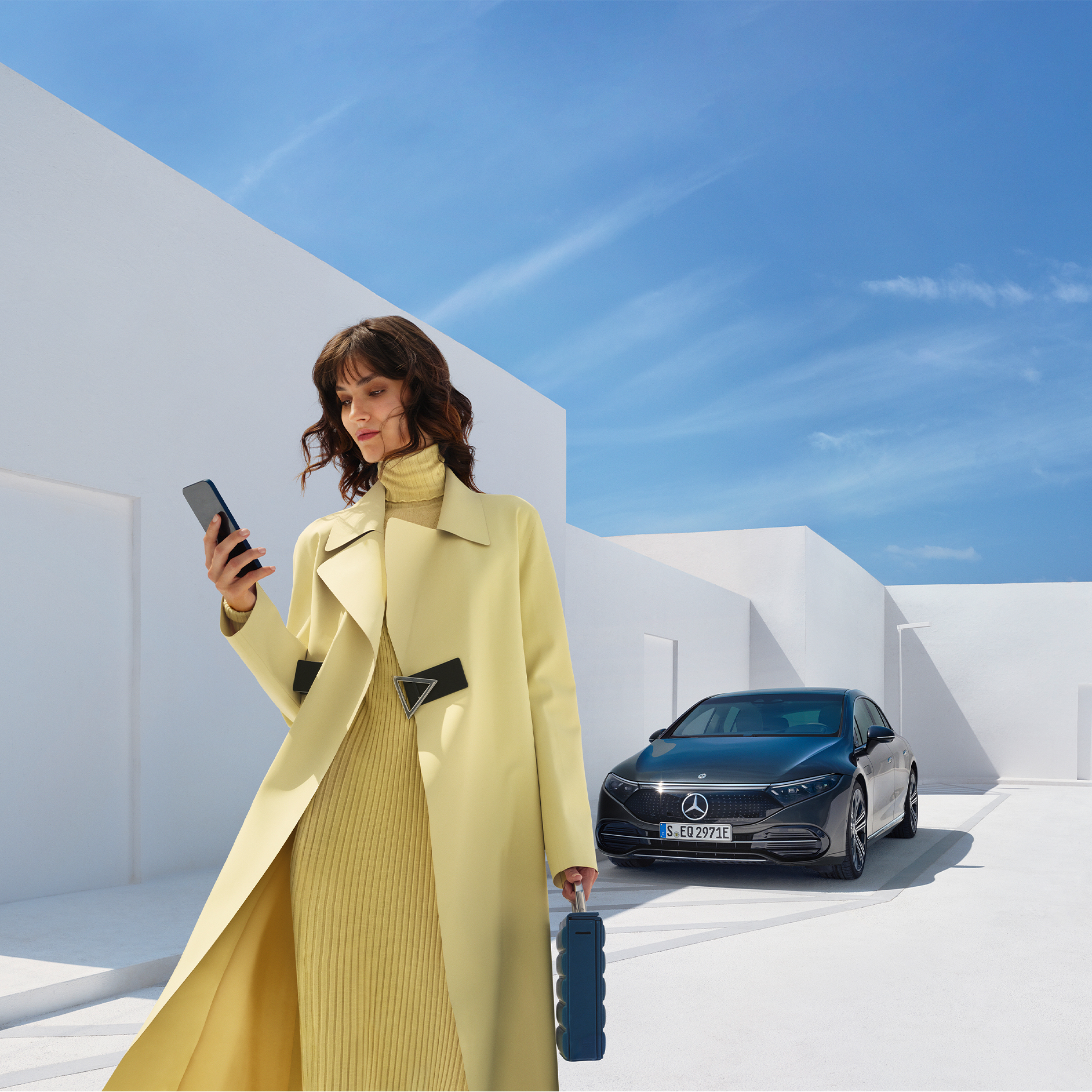 Acheter l’offre digitale | Divertissement | Mercedes me Une femme regarde son téléphone portable alors qu'elle s'éloigne de sa modèles électrique de Mercedes-Benz.