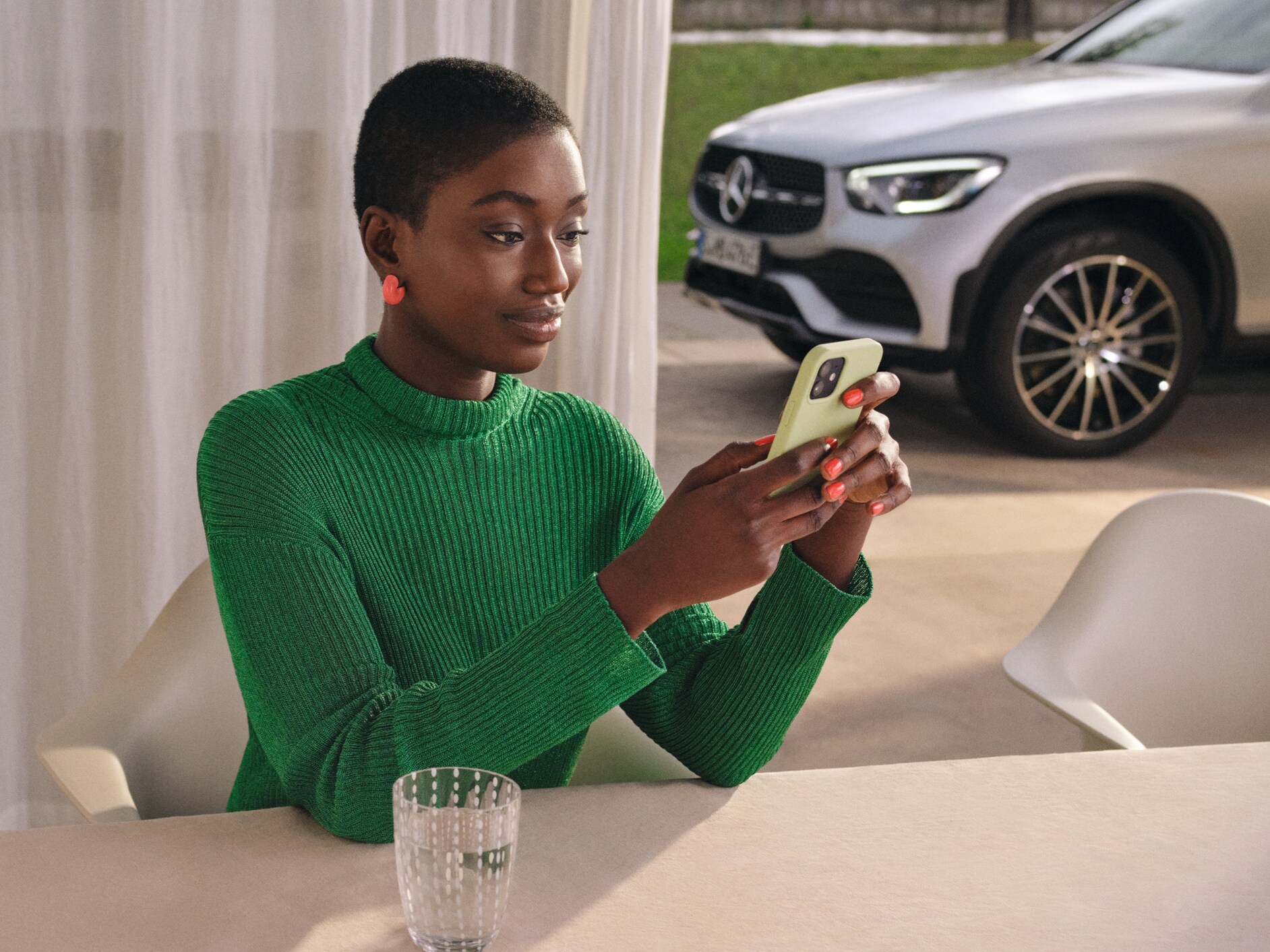 Eine Frau kontrolliert mit dem Smartphone den Status Ihres Fahrzeugs.