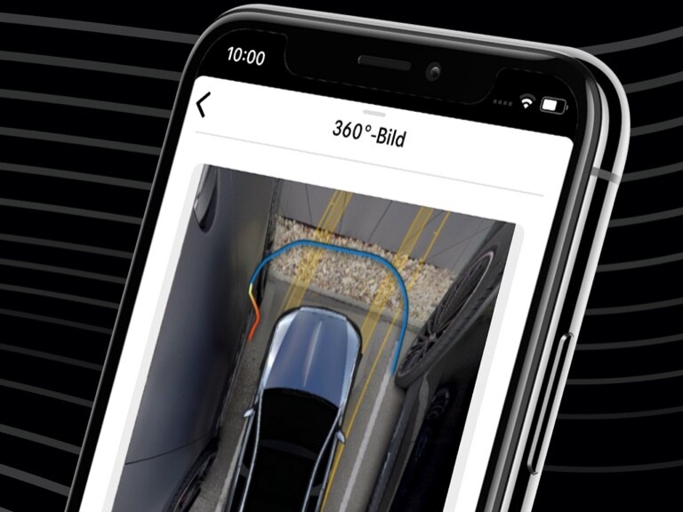 Per Mercedes-Benz Remote Parking App auf dem Smartphone und der 360°-Ansicht wird ein Mercedes-Benz bequem in eine enge Parklücke gesteuert.