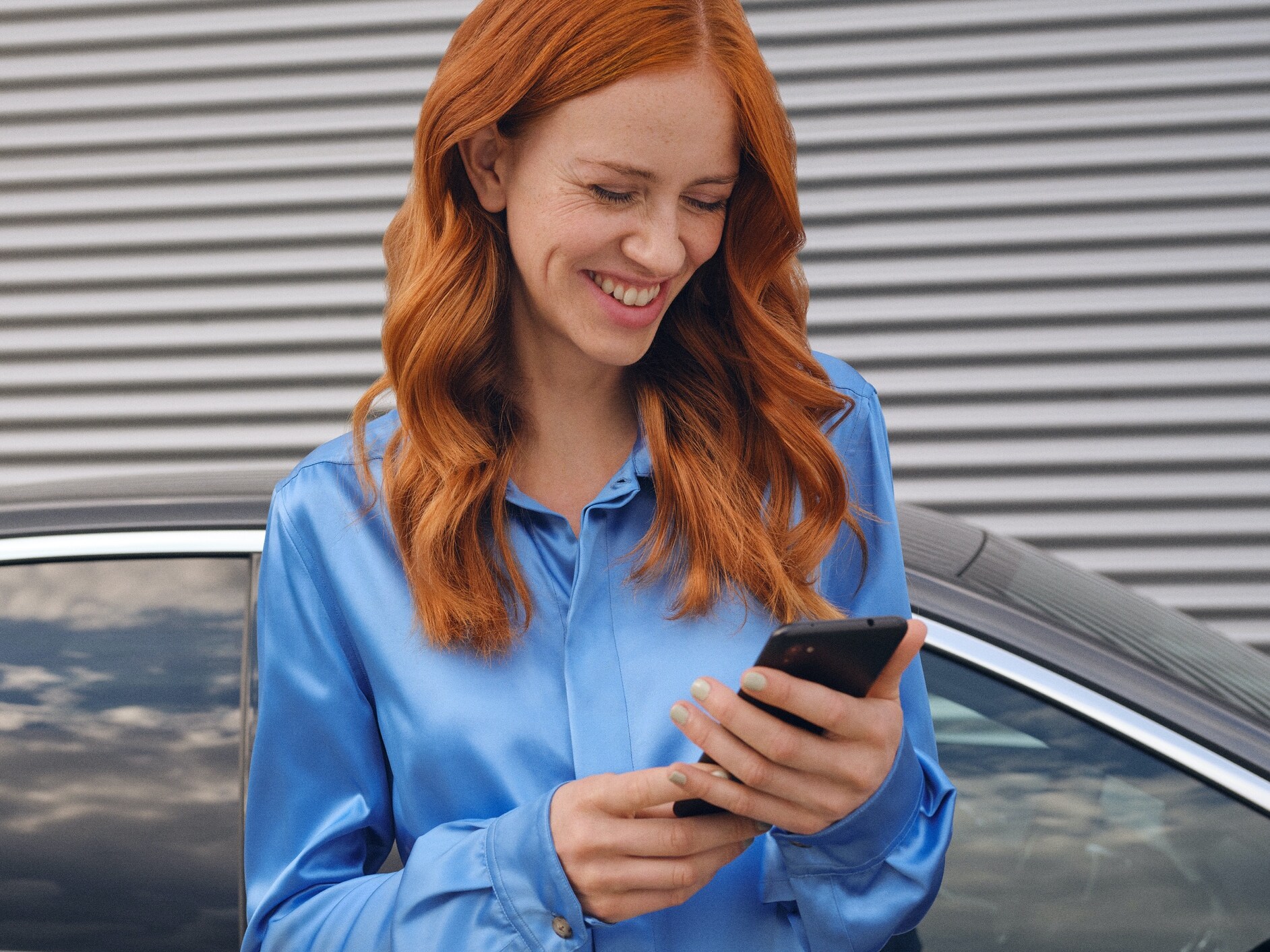 Une femme se connecte à sa Mercedes-Benz via l’application Mercedes me sur son smartphone.