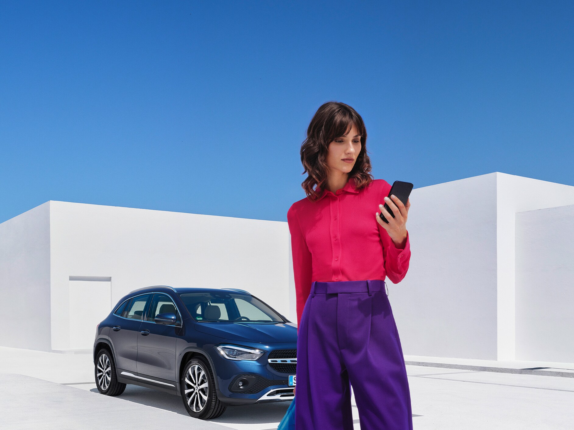 Eine Frau stellt per Mercedes me App auf ihrem Smartphone eine Verbindung mit ihrem Mercedes-Benz her.