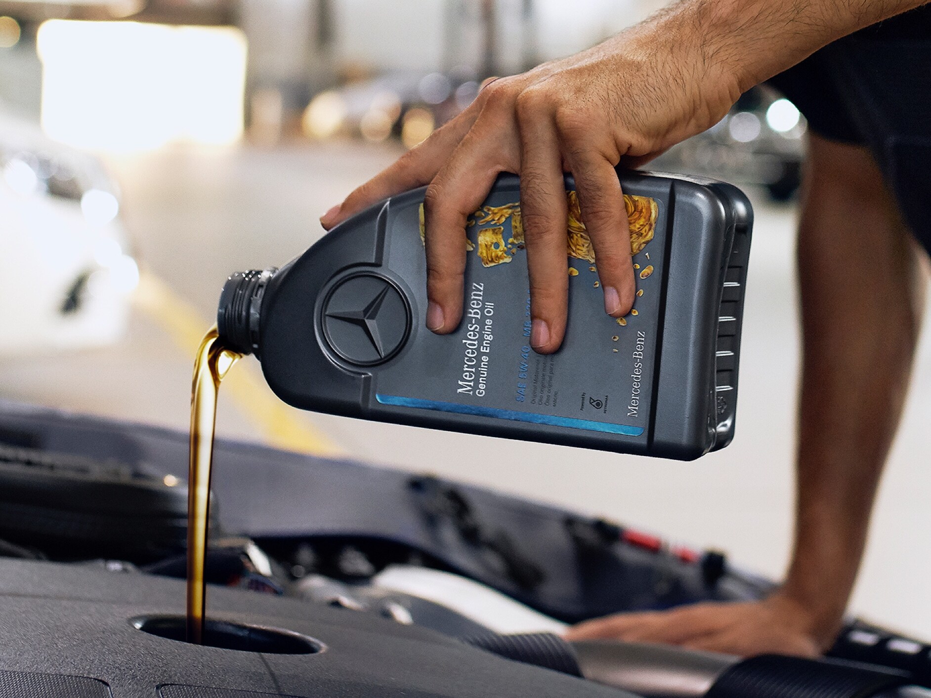 Eine Person, die Motoröl in das Mercedes-Benz Fahrzeug einfüllt.