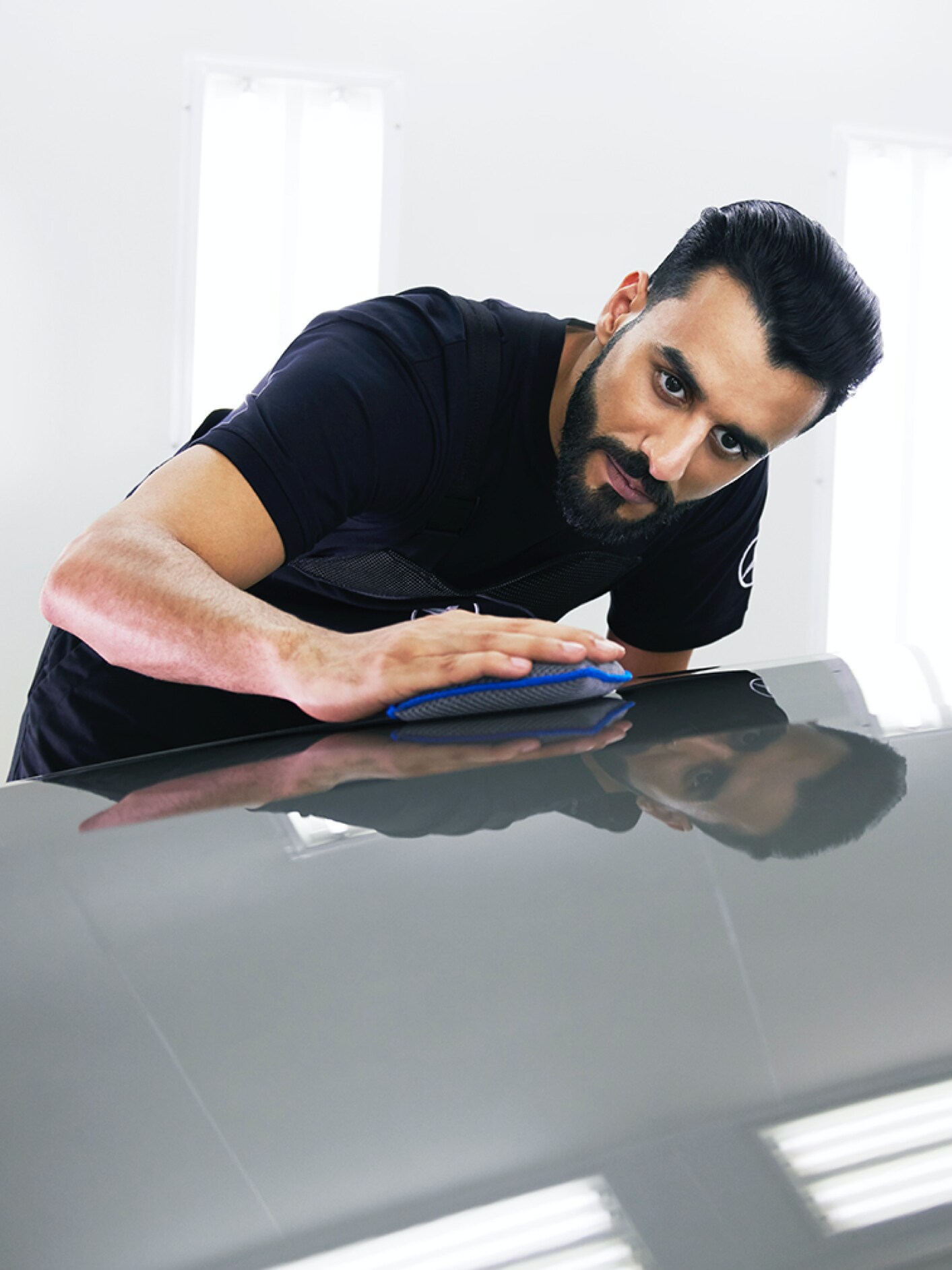 Ein Mercedes-Benz Techniker überprüft die Motorhaube auf kleine Schäden.