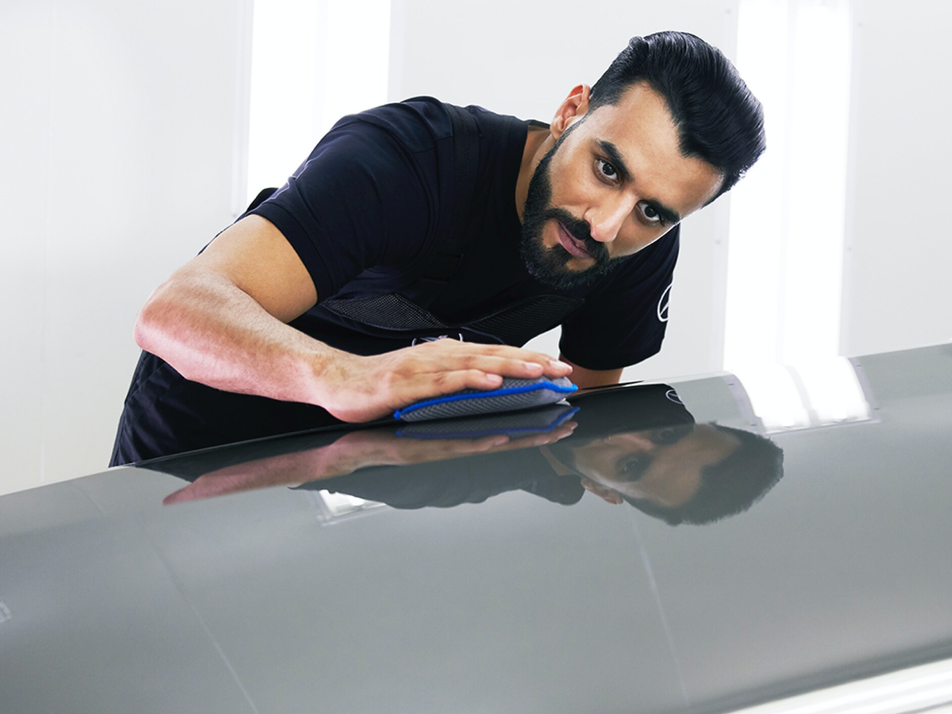 Ein Mercedes-Benz Techniker überprüft die Motorhaube auf kleine Schäden.