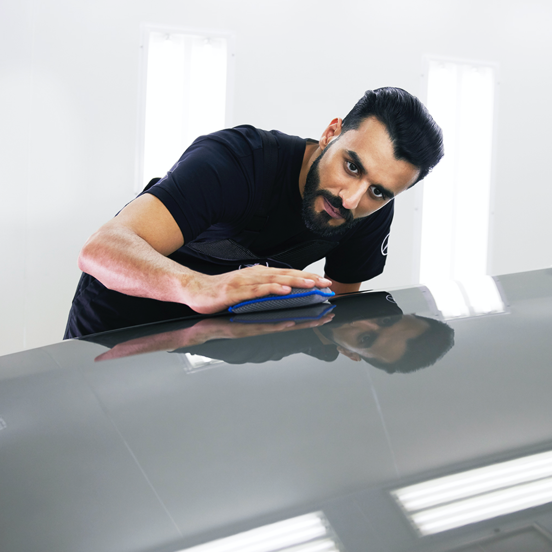 SmallRepair Ein Mercedes-Benz Techniker überprüft die Motorhaube auf kleine Schäden.