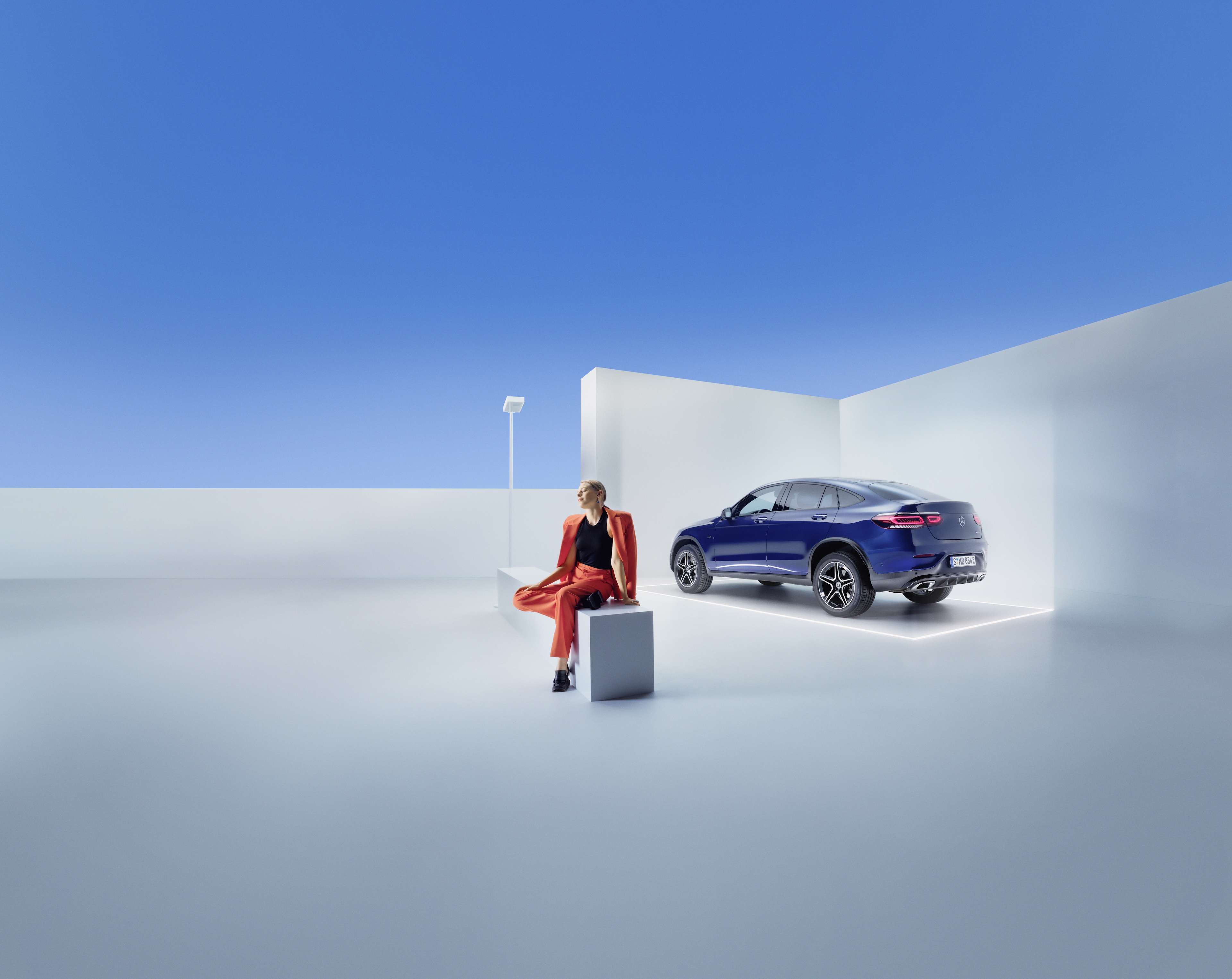 Mercedes-Benz Serviceverträge Eine Frau sitzt auf einer Bank vor einem Mercedes-Benz.