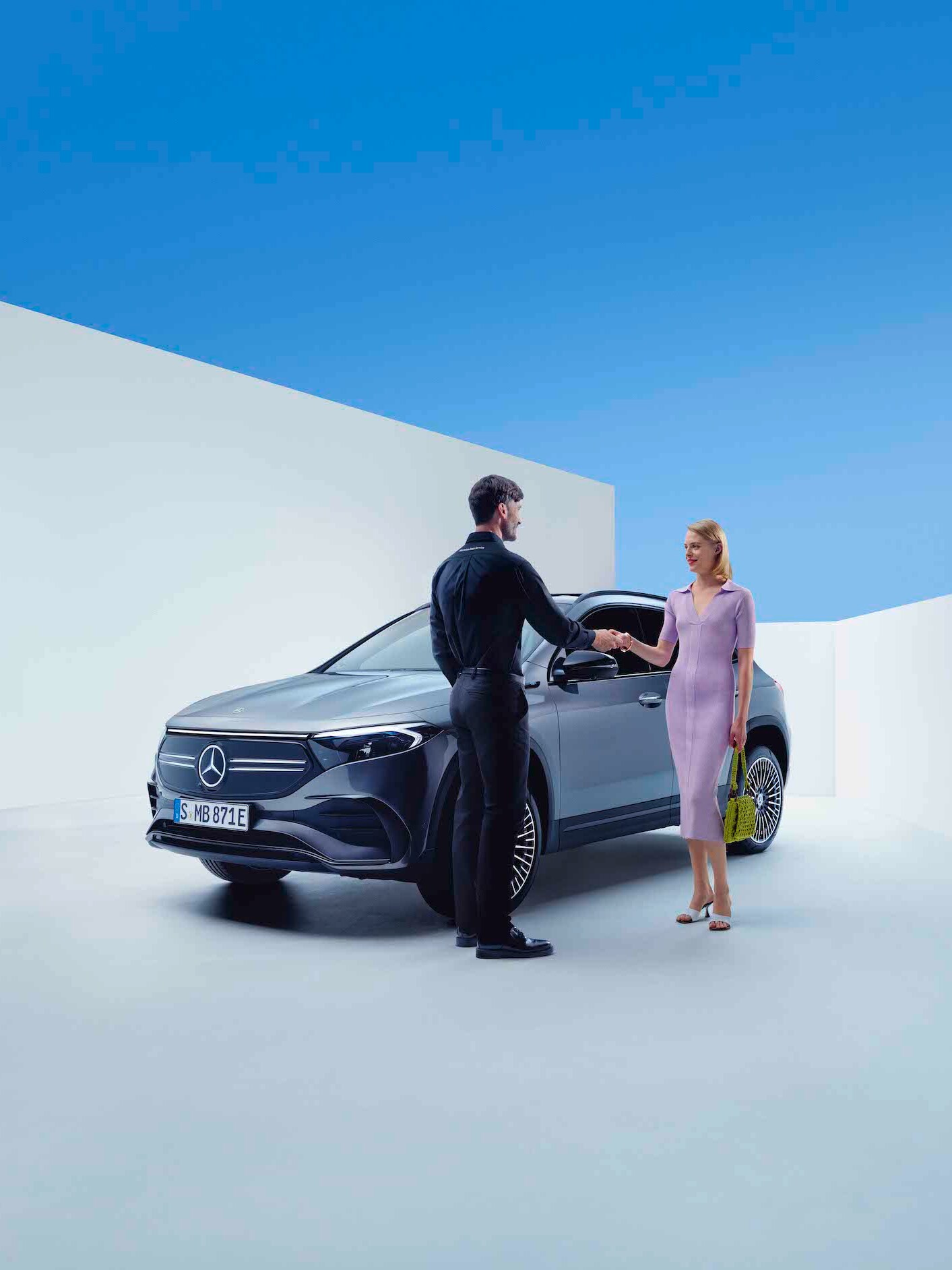 Ein Mann und eine Frau geben sich die Hand vor einem Mercedes-Benz.