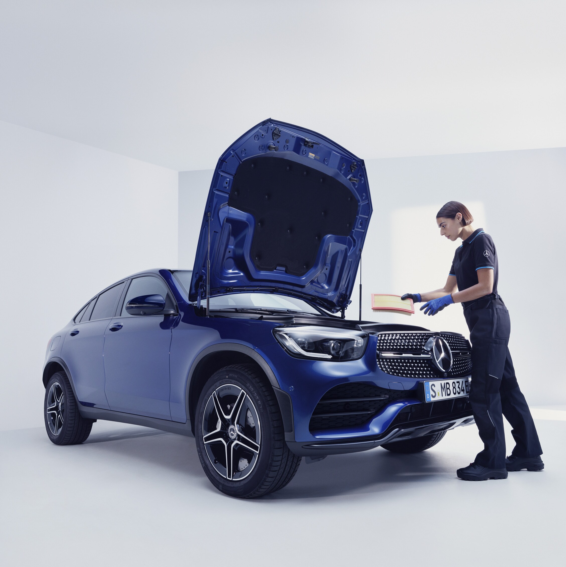 Ein Mercedes-Benz Mechaniker und ein Mann stehen vor der offenen Motorhaube eines Mercedes-Benz.