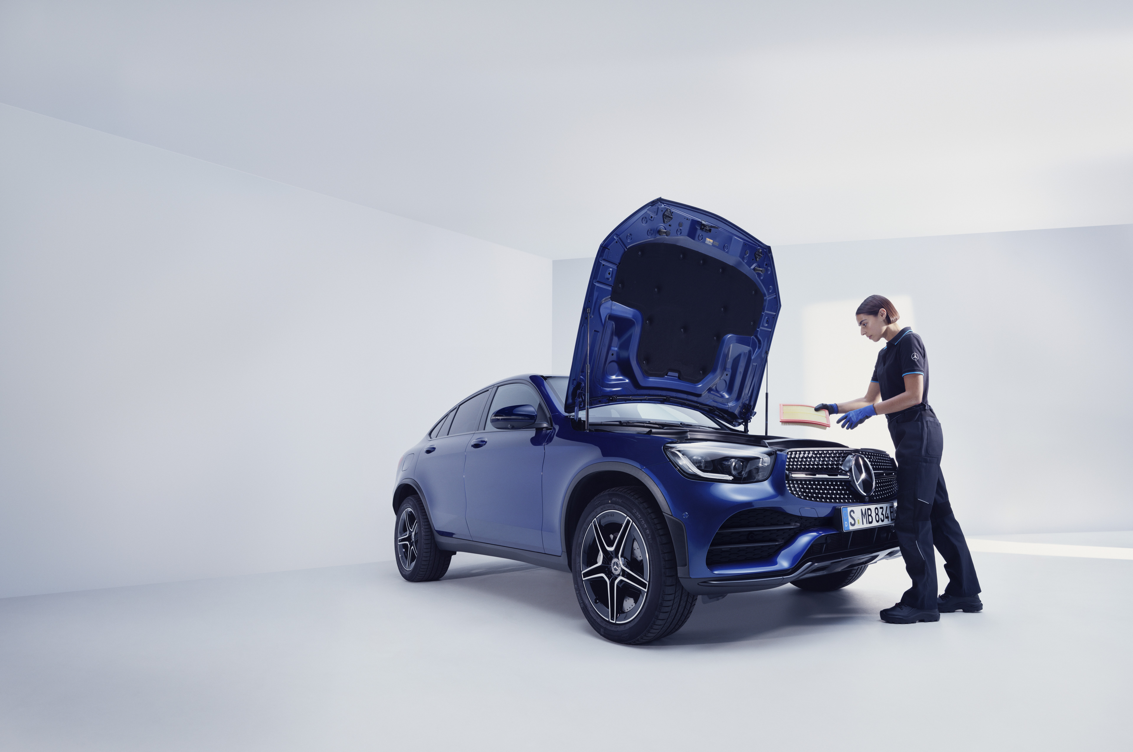 Mercedes-Benz Wartungs-Services Ein Mercedes-Benz Mechaniker und ein Mann stehen vor der offenen Motorhaube eines Mercedes-Benz.