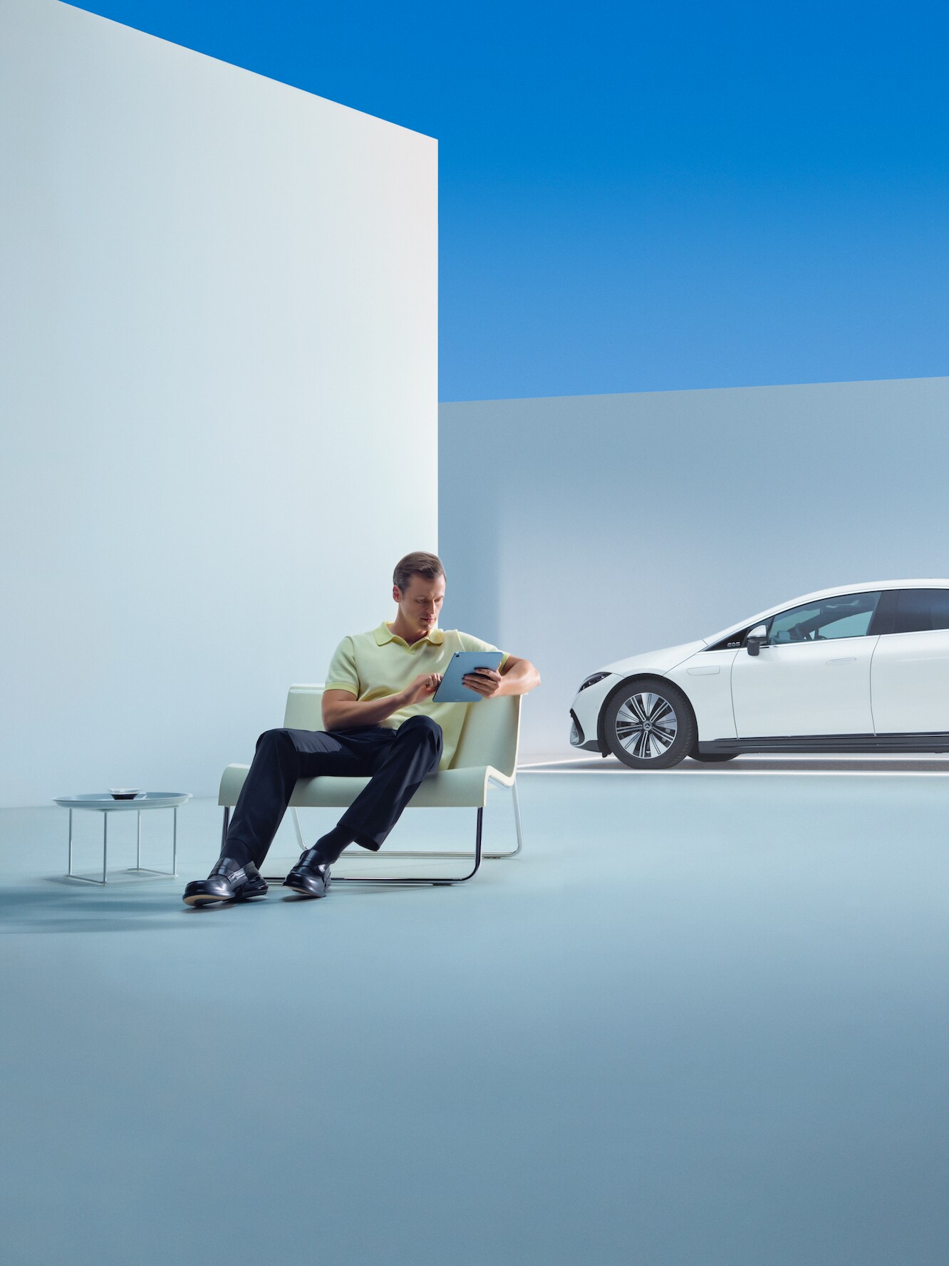 Eine entspannter Mann sitzt mit seinem Tablet vor seinem Mercedes.