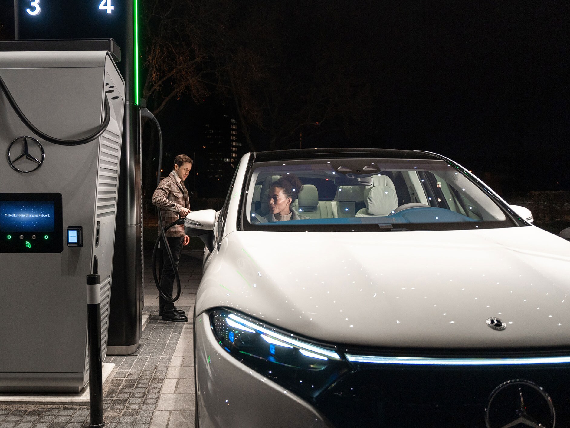 Une personne rechargeant une Mercedes-Benz EQS SUV sur une borne de recharge.