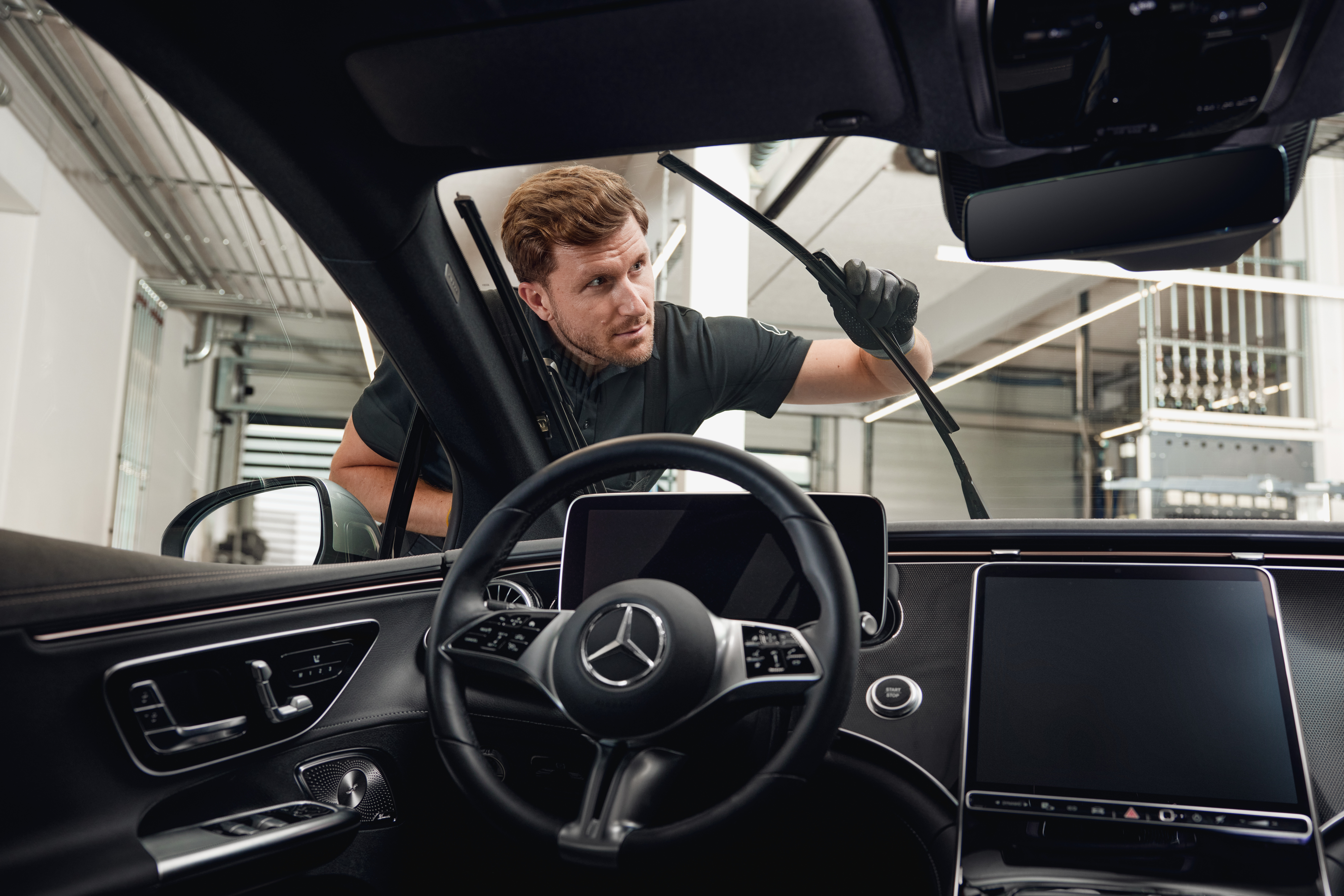 Original-Scheibenwischerblätter von Mercedes-Benz Innenansicht eines Mercedes-Benz-Fahrzeugs, in dem ein Techniker Original-Scheibenwischerblätter austauscht.