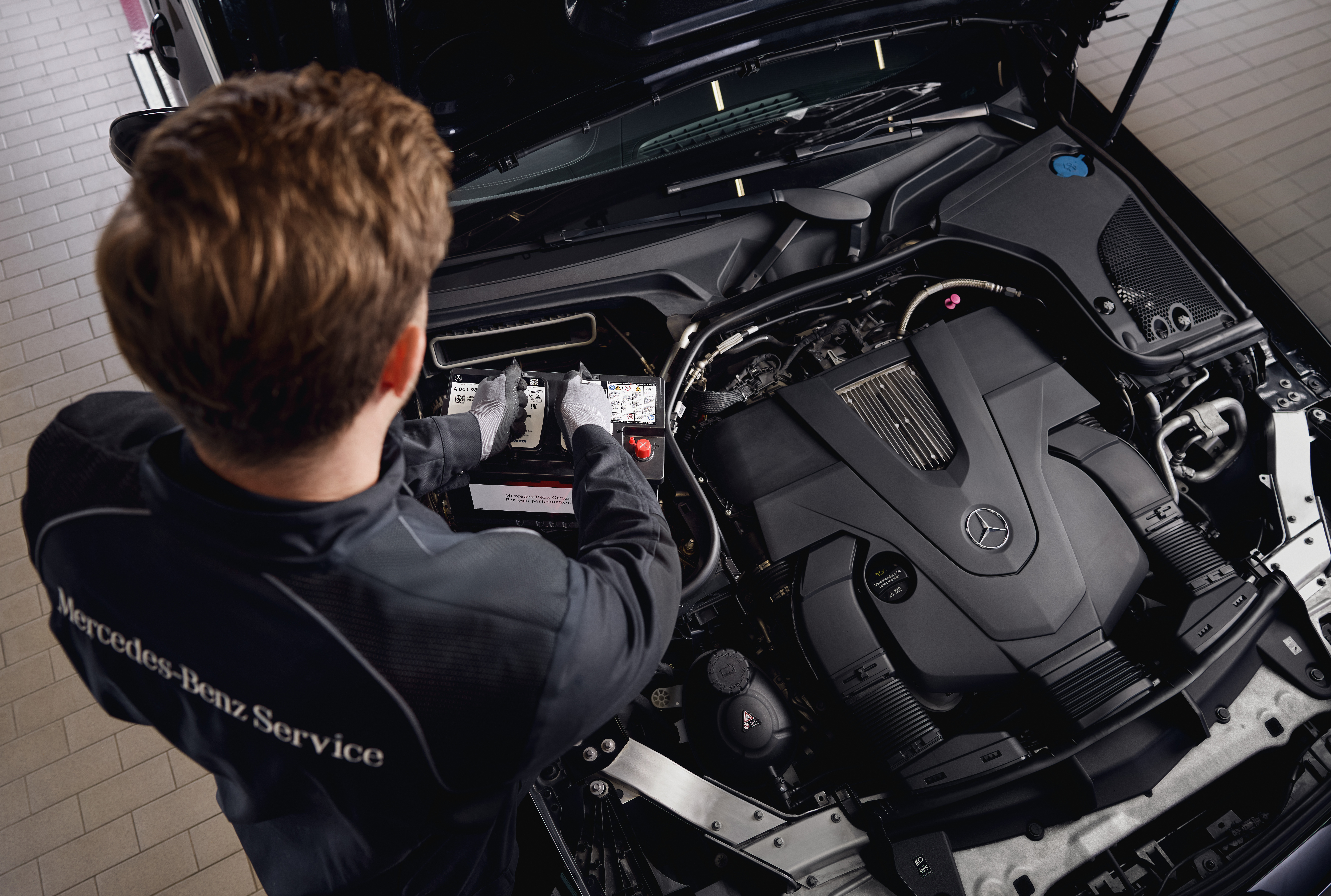 Original-Starterbatterien von Mercedes-Benz Motorservice in einer Werkstatt, bei dem der Austausch von Bauteilen unter Verwendung von Mercedes-Benz Originalteilen gezeigt wird.