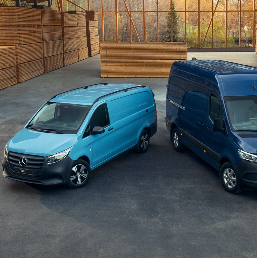 Deux fourgons Mercedes-Benz bleus dans un entrepôt en bois.