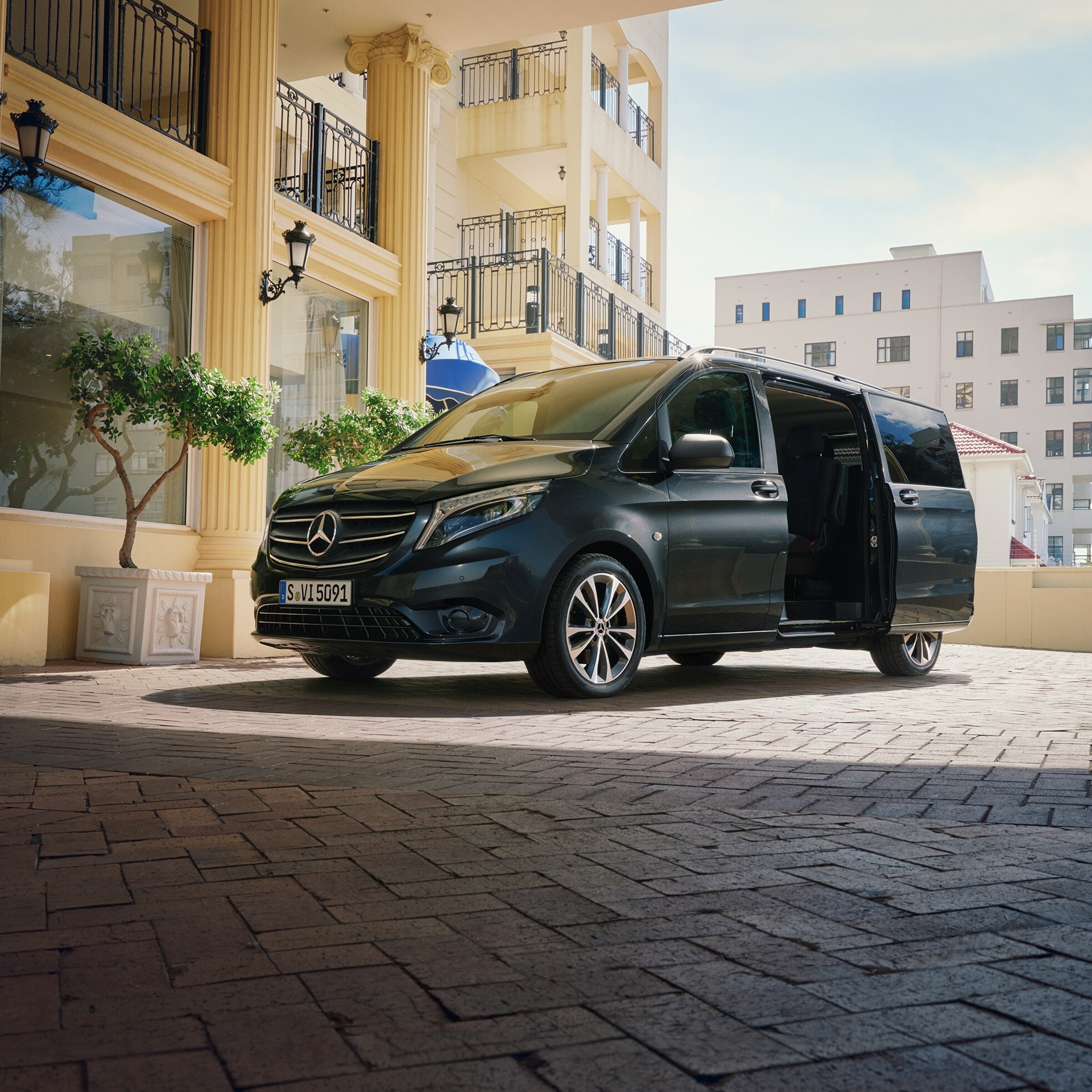 Une Mercedes-Benz Vito Tourer garée devant l'entrée d'un immeuble haut de gamme