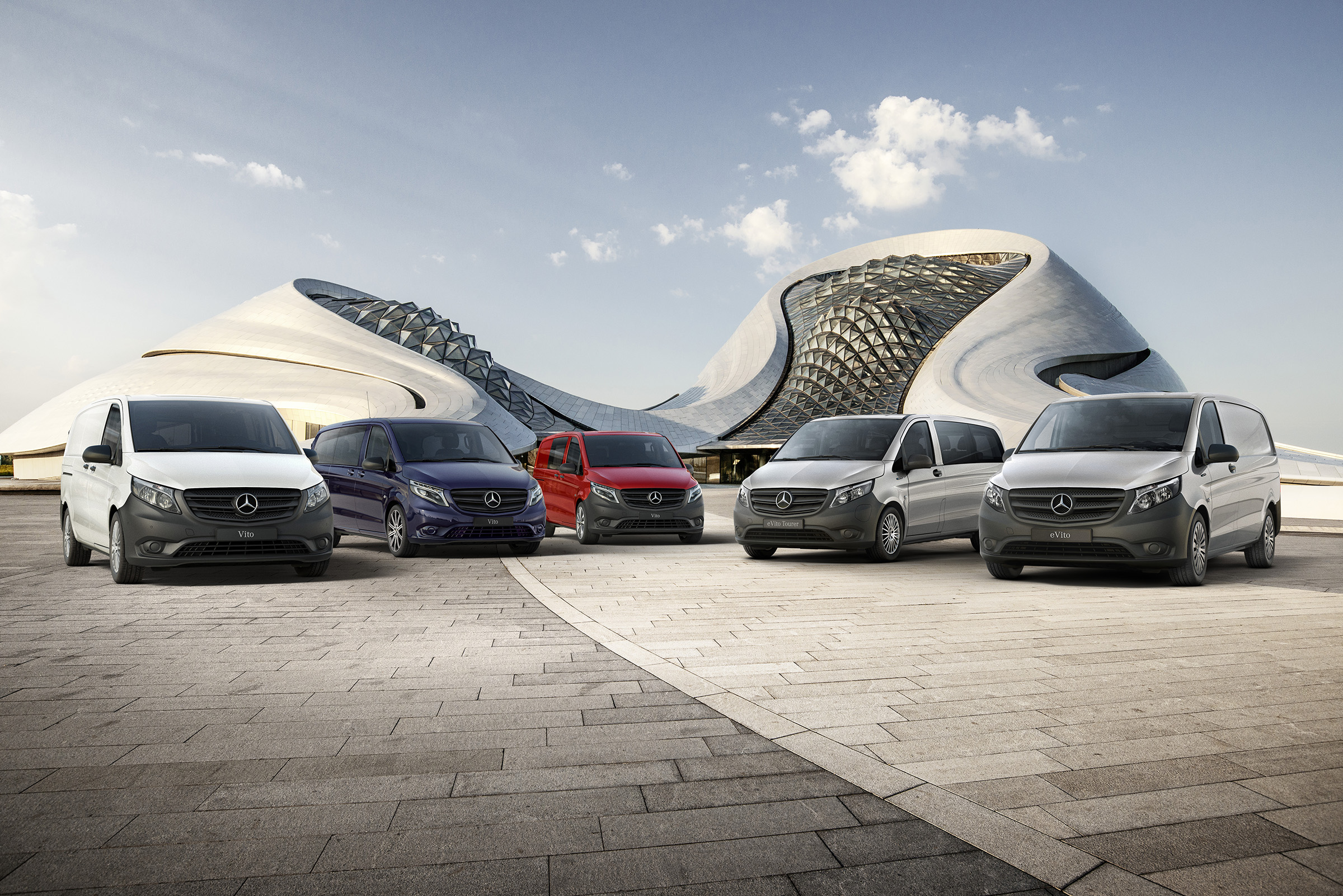 Gamme Vito | Tous les modèles Vito | Fourgons Mercedes-Benz Le Mercedes-Benz eVito Fourgon, le Vito Fourgon, le Vito Mixto, l'eVito Tourer et le Vito Tourer sont alignés côte à côte devant un bâtiment futuriste