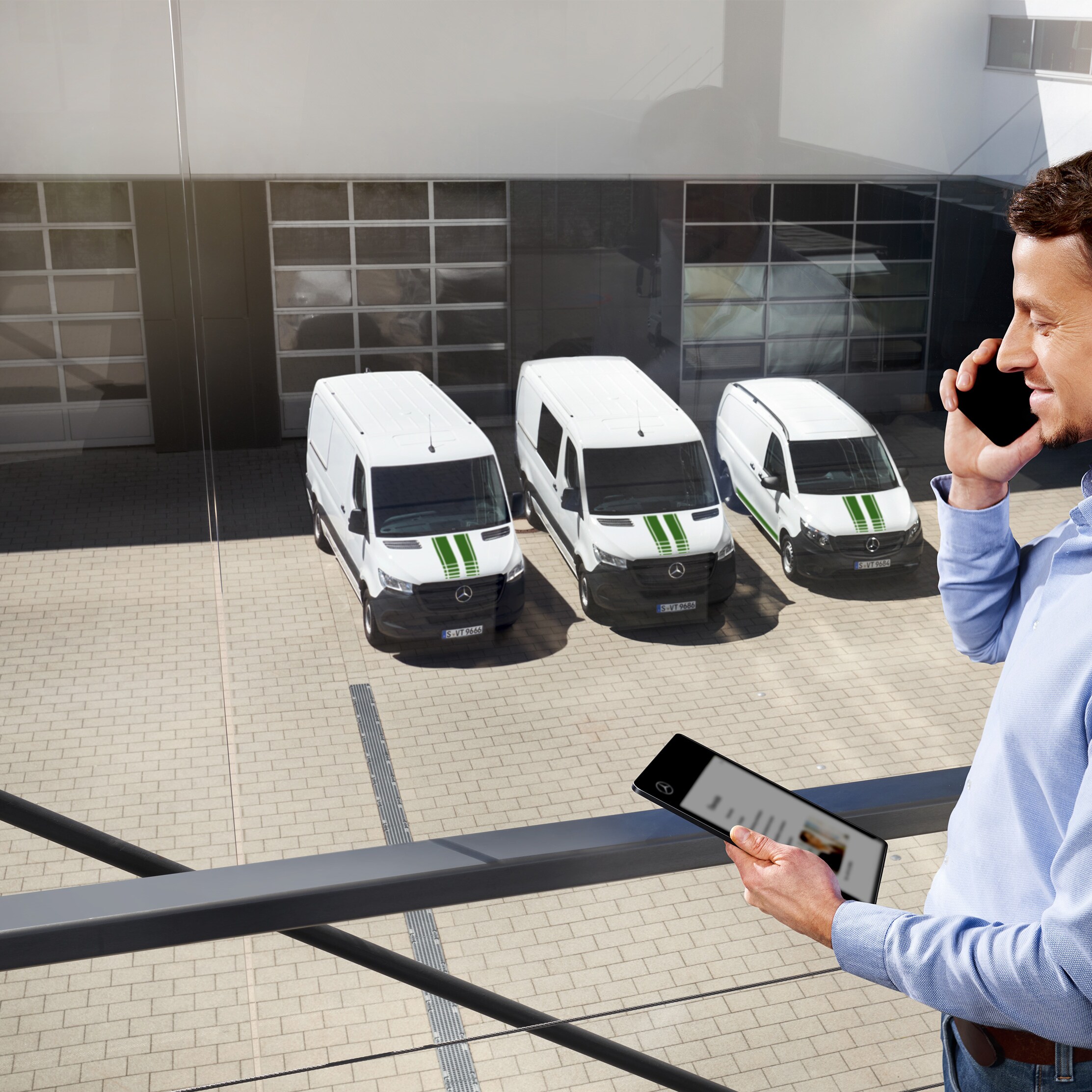 Ein Kunde telefoniert vor einer Flotte weißer Mercedes-Benz Transporter.