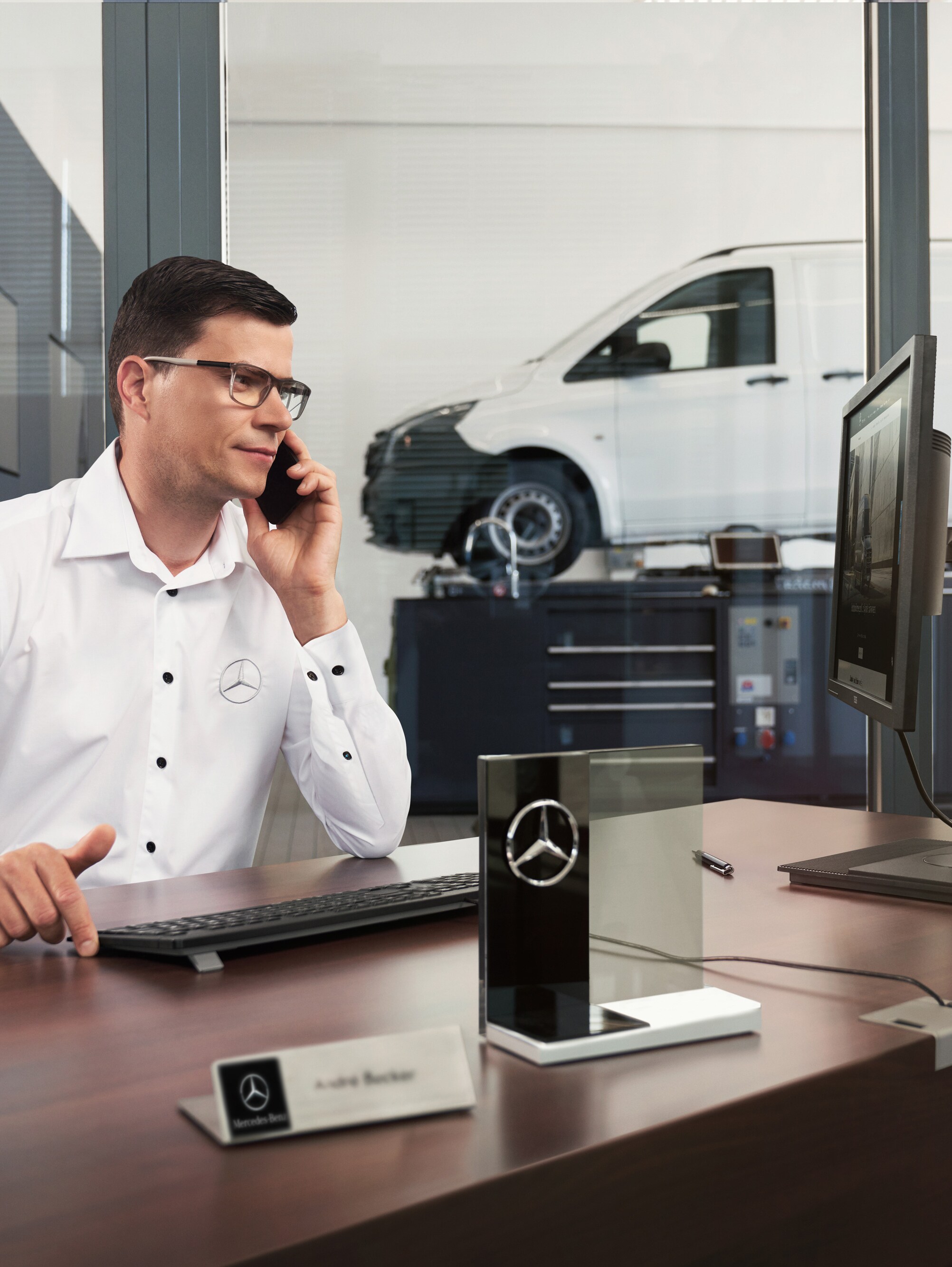 Conseiller après-vente Mercedes-Benz au téléphone dans un atelier.
