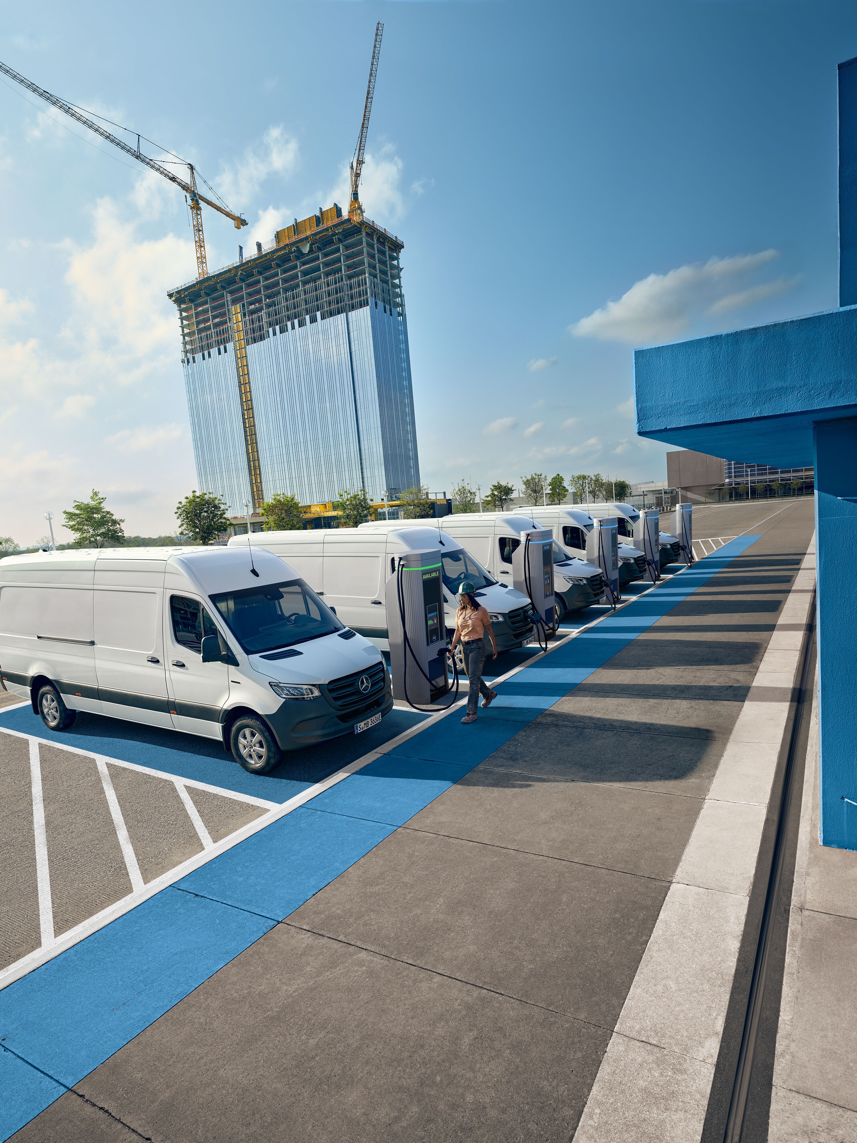 Eine Flotte weißer elektrischer Mercedes-Benz Transporter parkt an einer Ladestation.