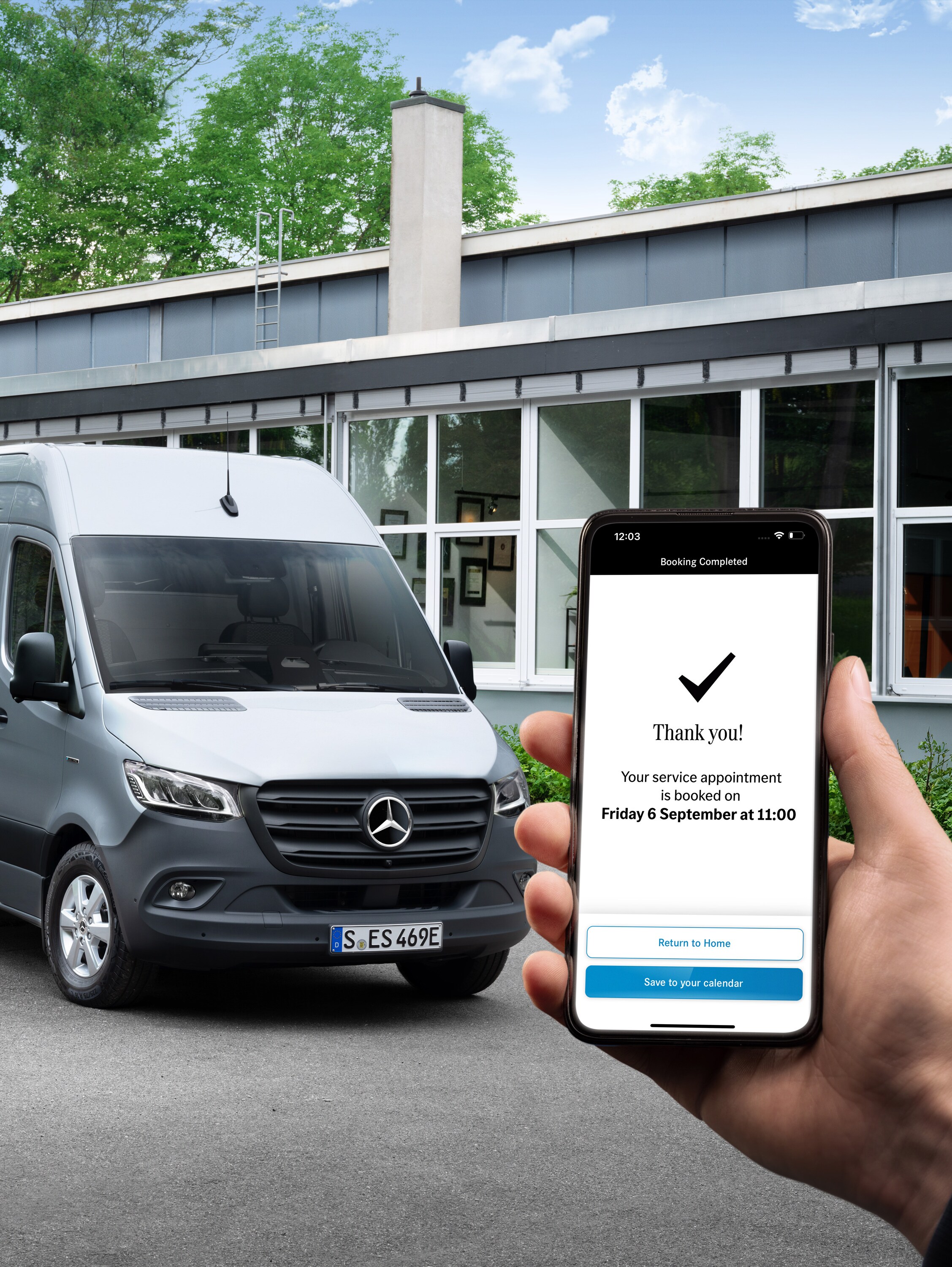 Ein grauer Mercedes-Benz Sprinter Transporter vor einem Büro mit einer Person, die ein Smartphone in der Hand hält im Vordergrund.