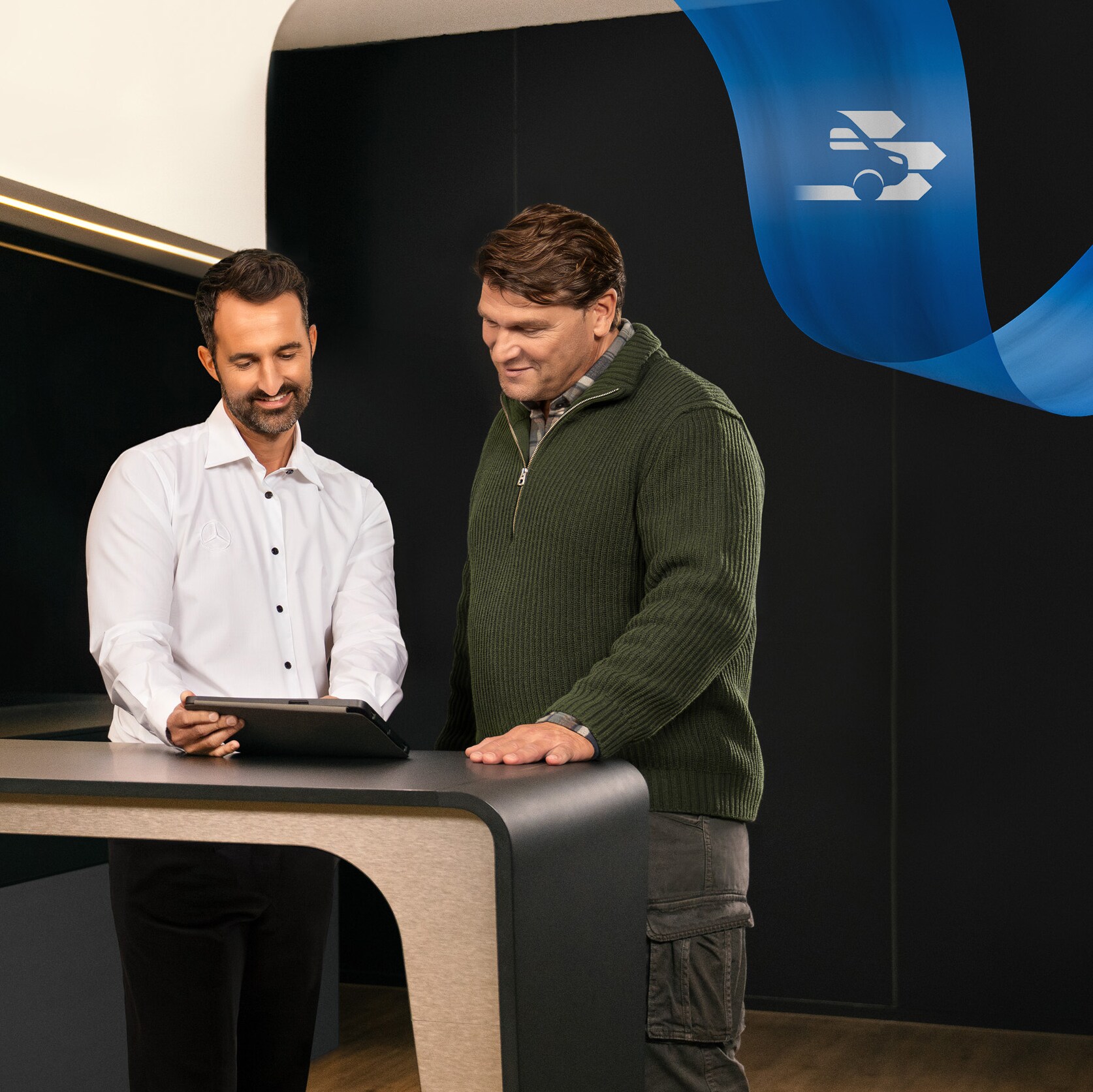 Zwei Männer stehen im Büro eines Mercedes-Benz Servicepartners und diskutieren über etwas, das sie auf einem Tablet gesehen haben