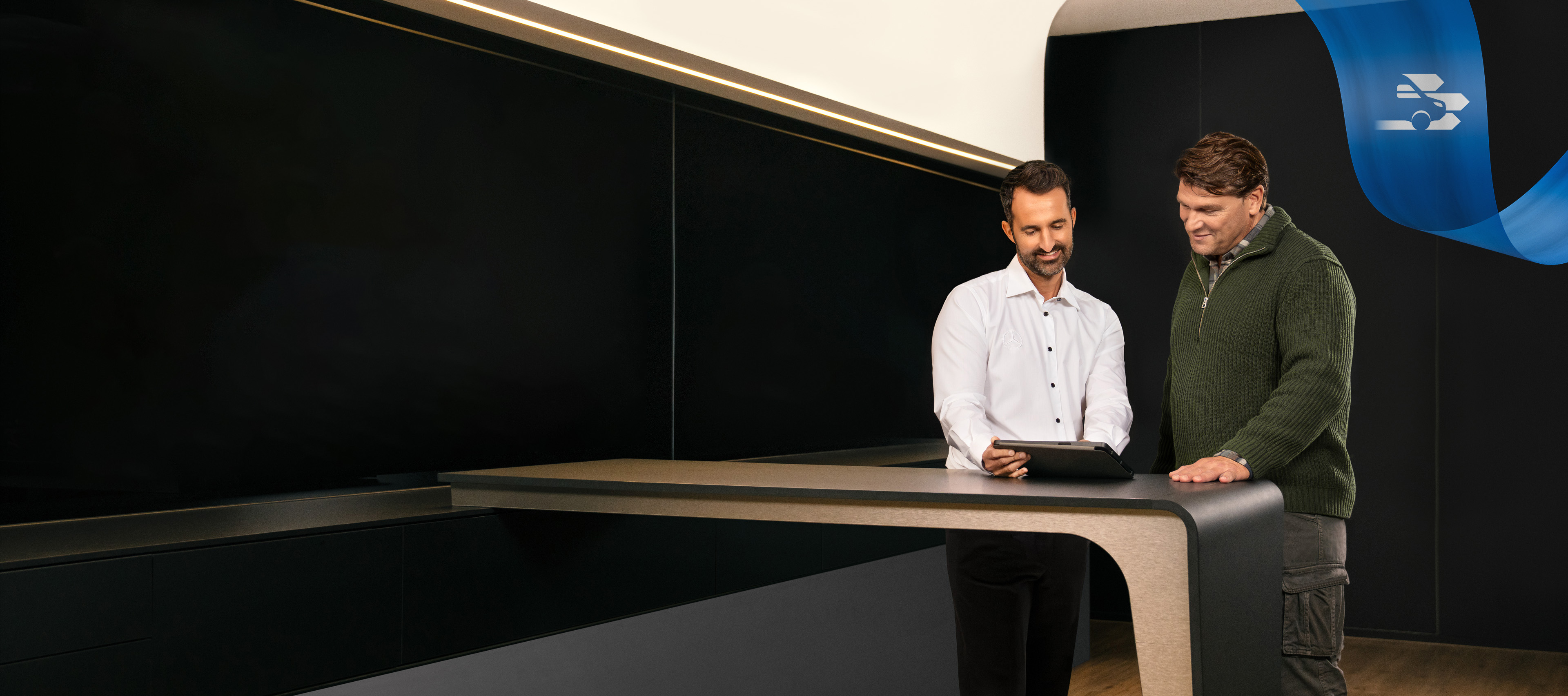 Mercedes-Benz | Komfort | Servicepartner Zwei Männer stehen im Büro eines Mercedes-Benz Servicepartners und diskutieren über etwas, das sie auf einem Tablet gesehen haben