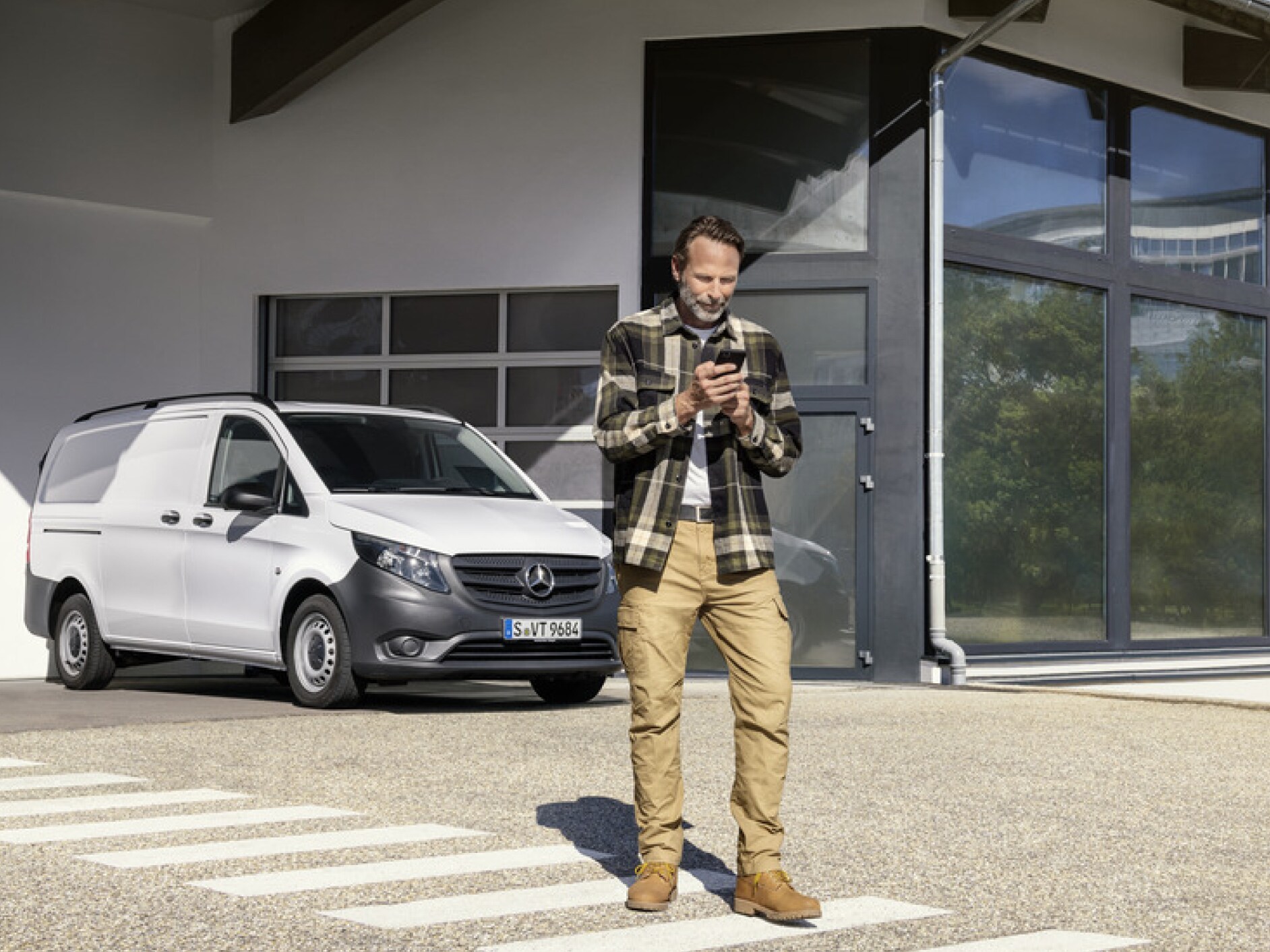 Eine Person mit Smartphone vor einem Mercedes-Benz Vito.