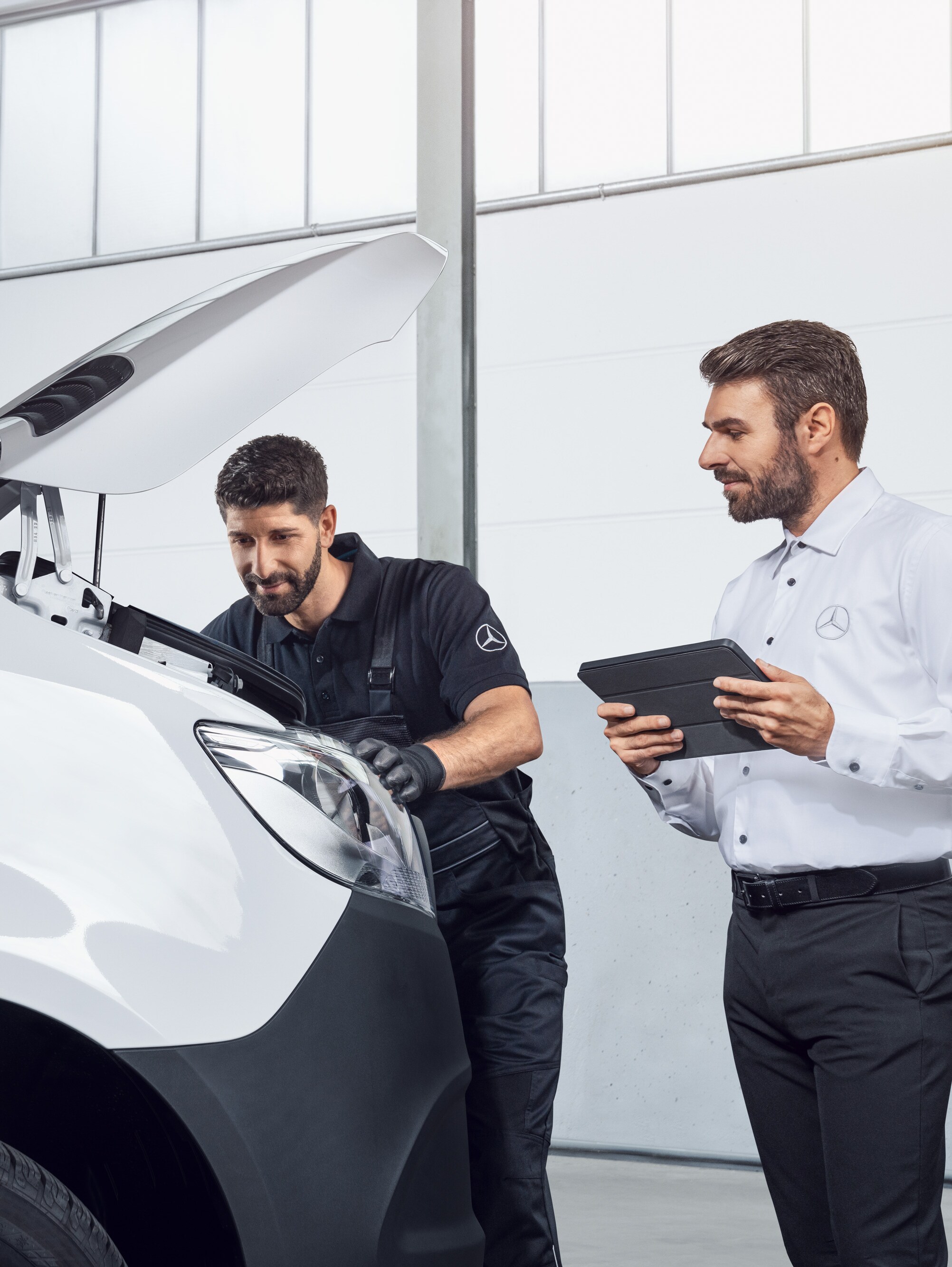 Zwei Männer testen einen Mercedes Sprinter mit Tablet und offener Motorhaube, Thema: Mercedes-Benz Sprinter Ersatzteile.