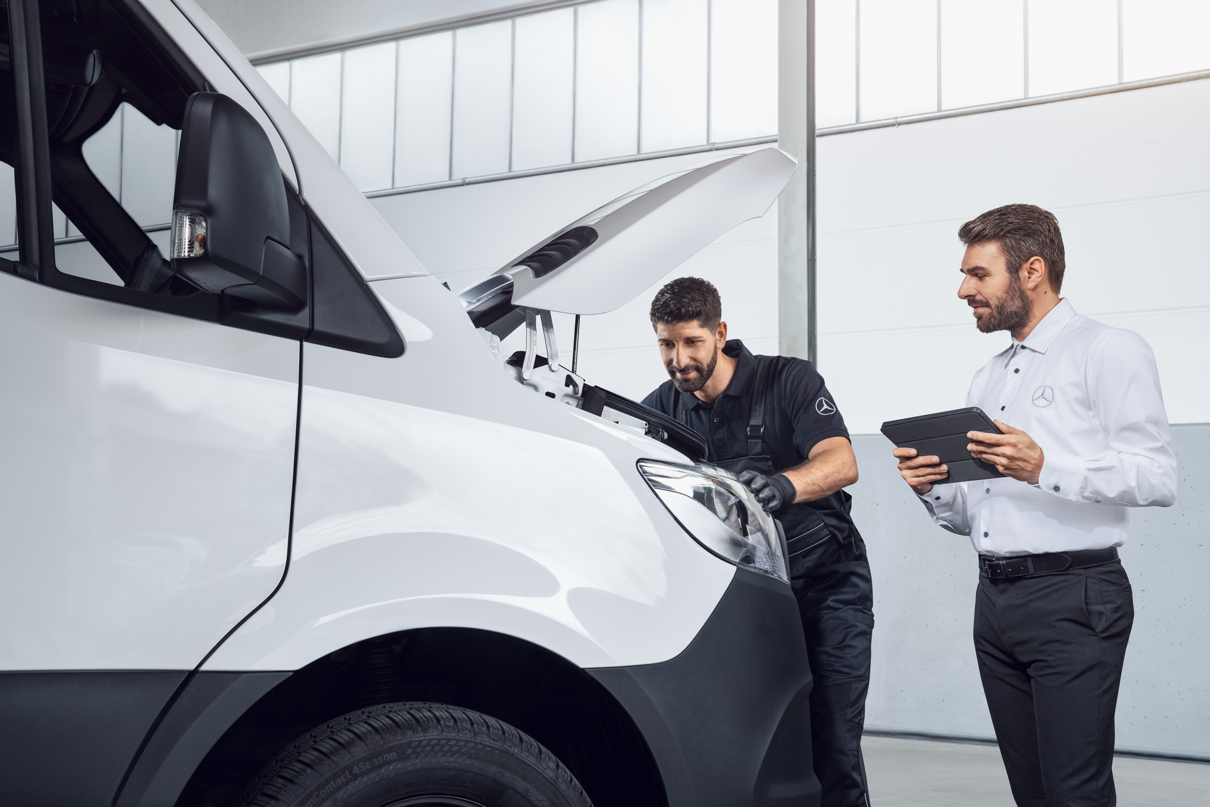 Mercedes-Benz | Transporter Qualität Original-Teile Zwei Männer testen einen Mercedes Sprinter mit Tablet und offener Motorhaube, Thema: Mercedes-Benz Sprinter Ersatzteile.