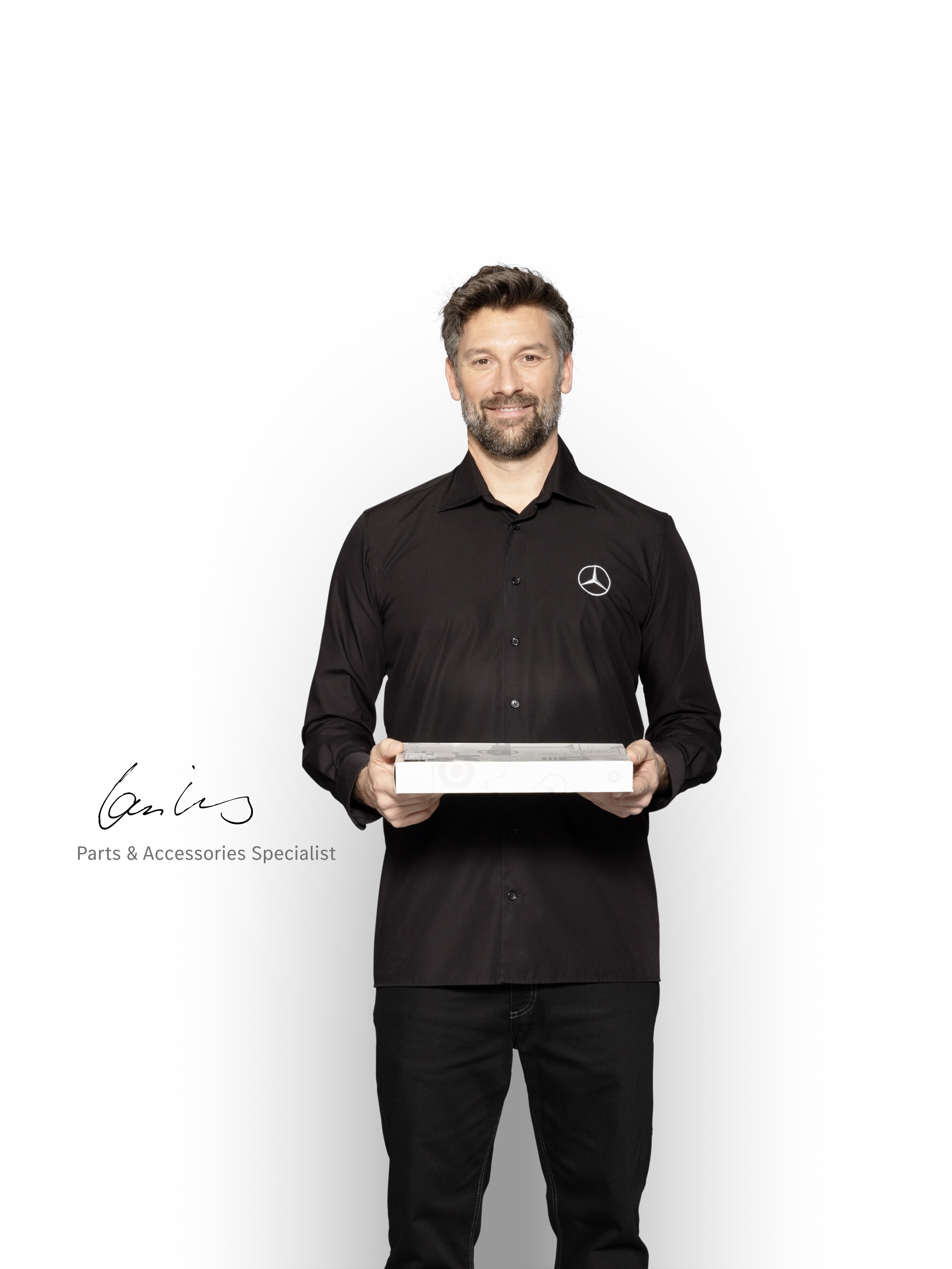 Technicien interne Mercedes-Benz avec une boîte dans les mains pour montrer les pièces d'origine Mercedes-Benz.