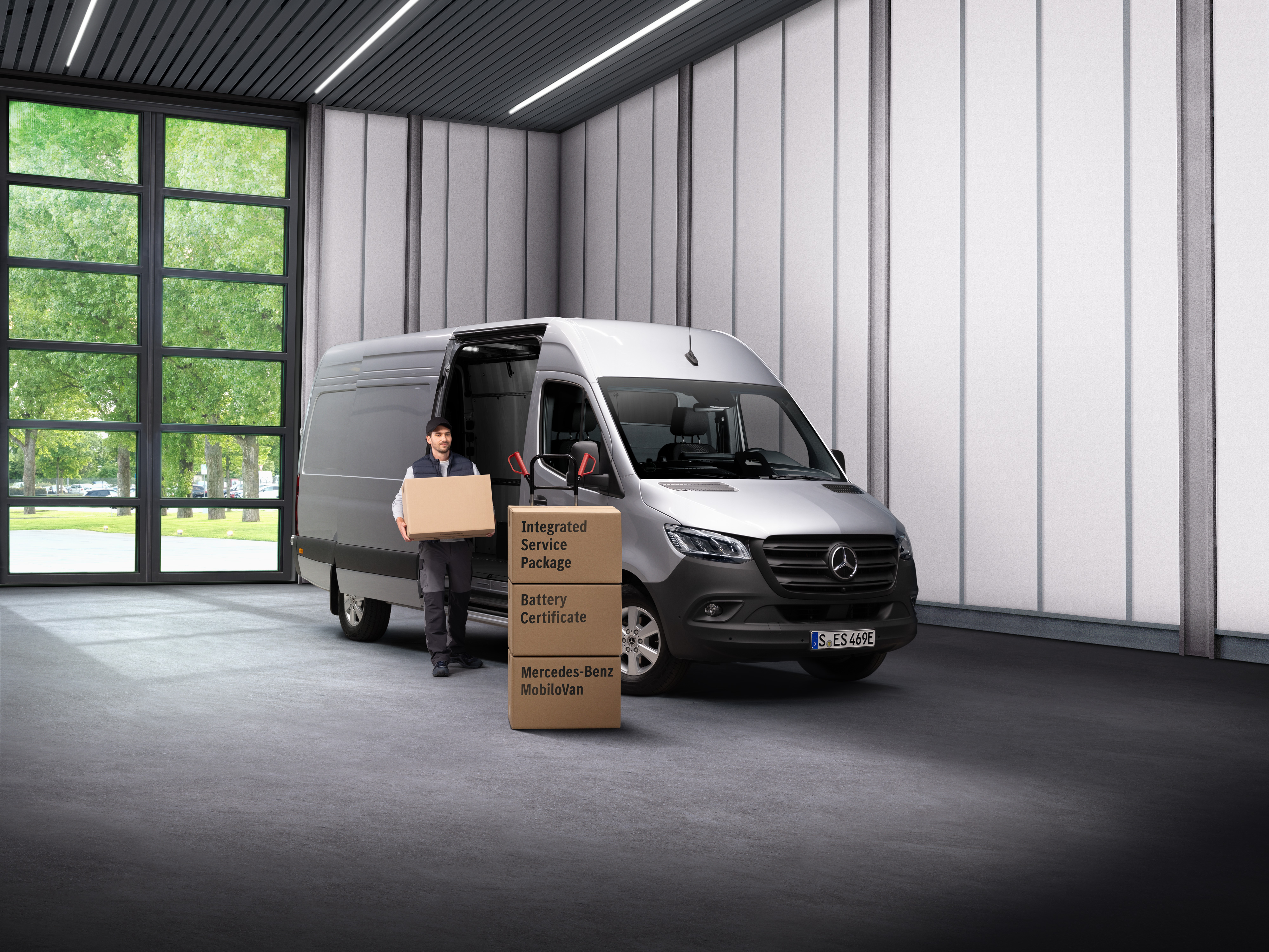 Mercedes-Benz - Services pour véhicules électriques Un employé du service électrique de Mercedes-Benz transportant des boîtes hors d’une agence de transport