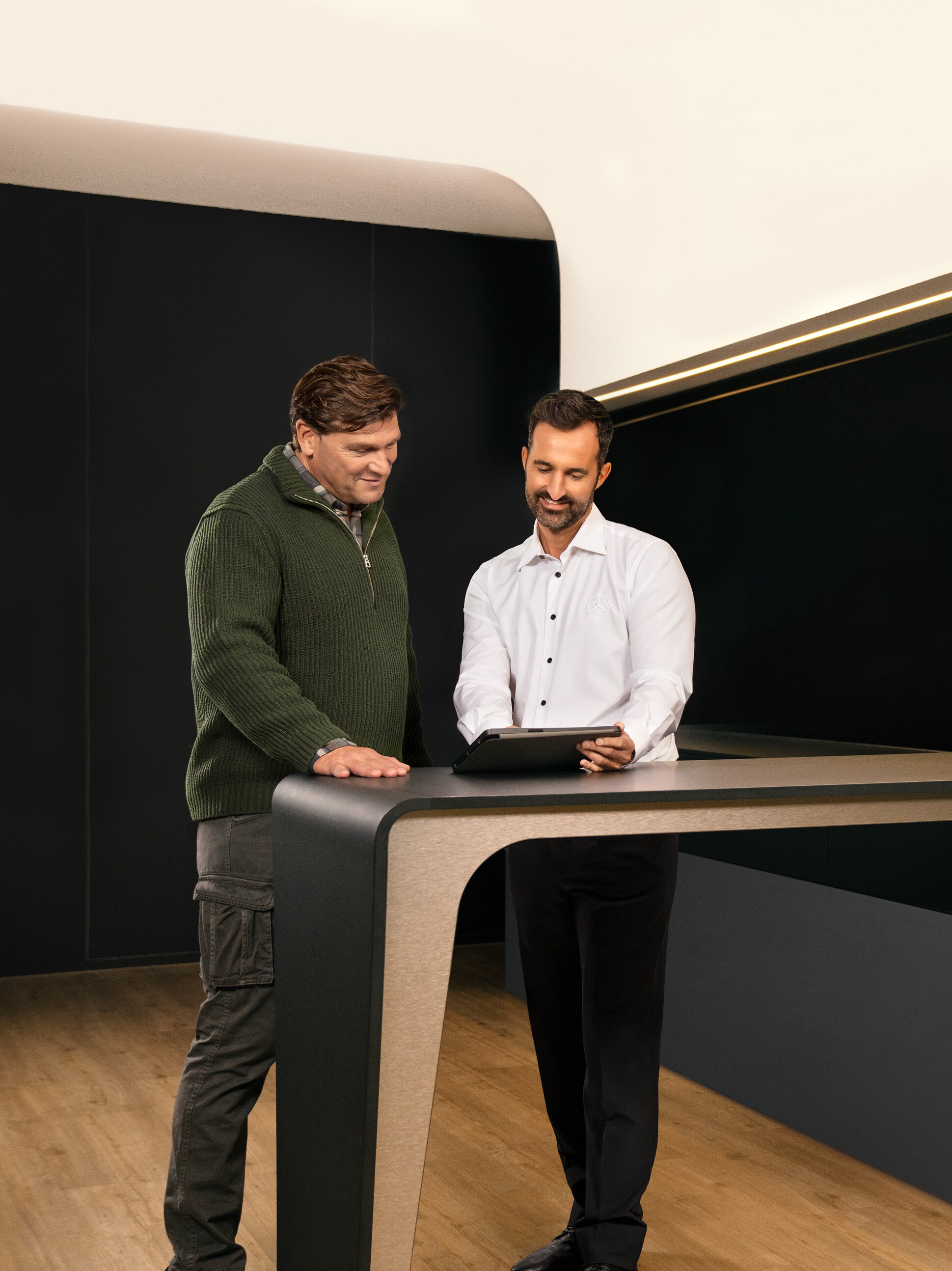 Zwei Männer diskutieren den Nutzfahrzeugservice von Mercedes-Benz über einem Tablet.