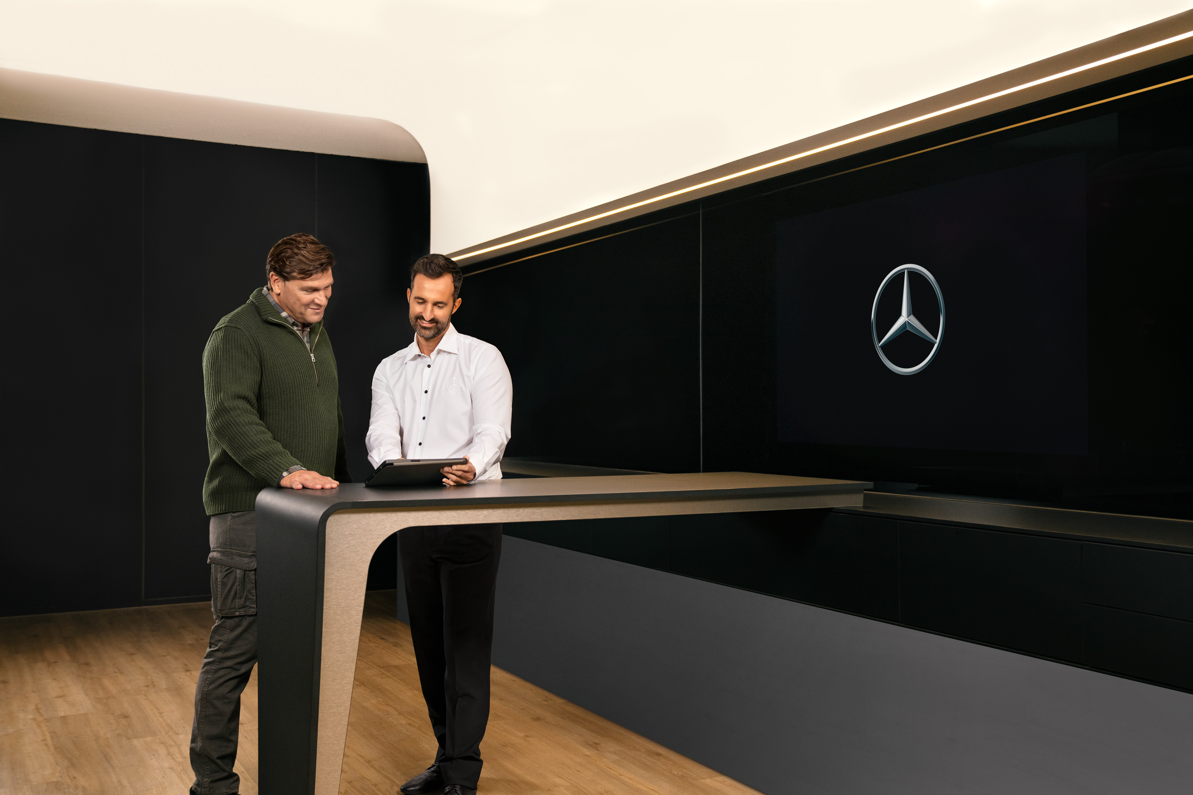 Mercedes-Benz | Serviceübersicht | ServiceCare Zwei Männer diskutieren den Nutzfahrzeugservice von Mercedes-Benz über einem Tablet.