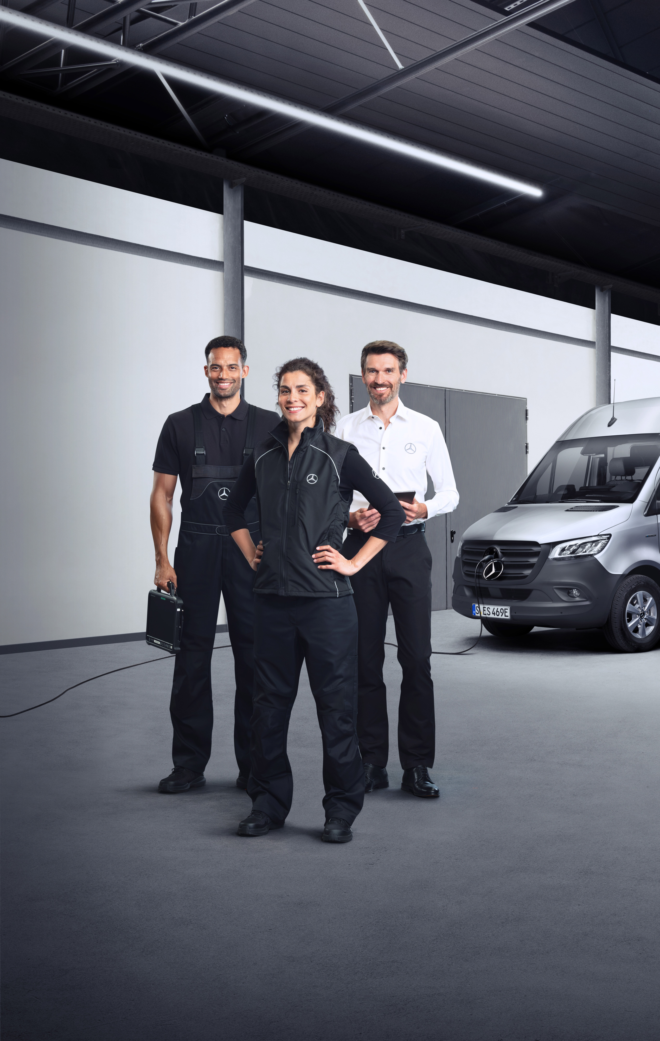Mercedes-Benz | Dienstleistungen im Überblick | Leistungen für Elektrotransporter Drei Mitarbeiter stehen vor einem silbernen Mercedes-Benz eSprinter mit angeschlossenem Ladekabel.