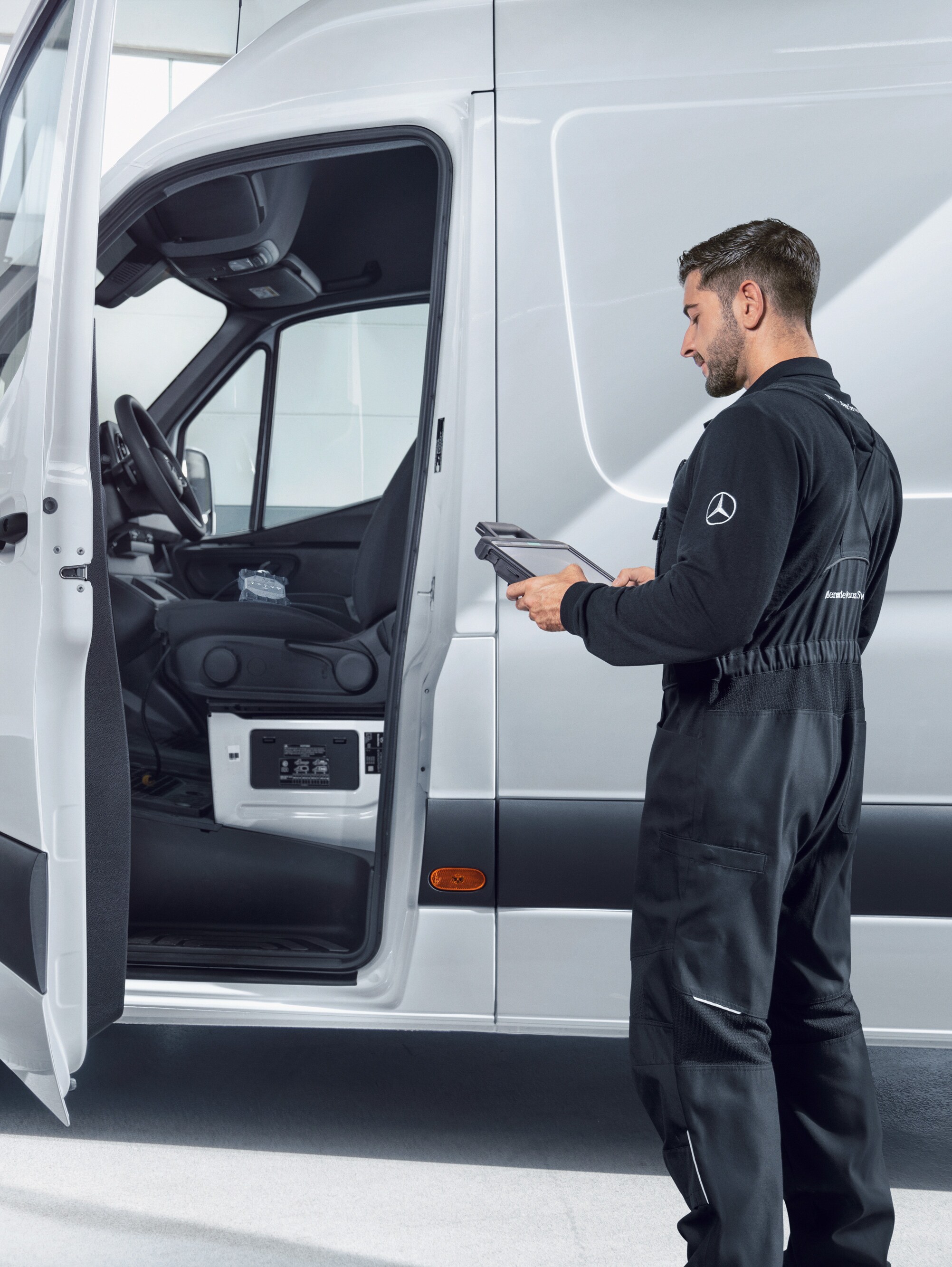 Un employé inspecte un utilitaire léger Mercedes-Benz offrant une qualité de service fiable pour la maintenance et les réparations.