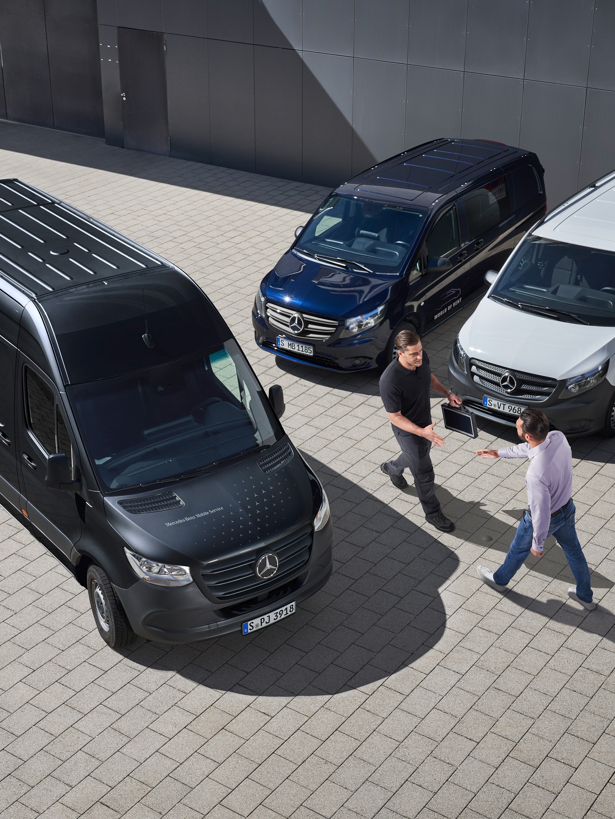 Zwei Männer grüßen sich zwischen Mercedes-Benz Transportern.