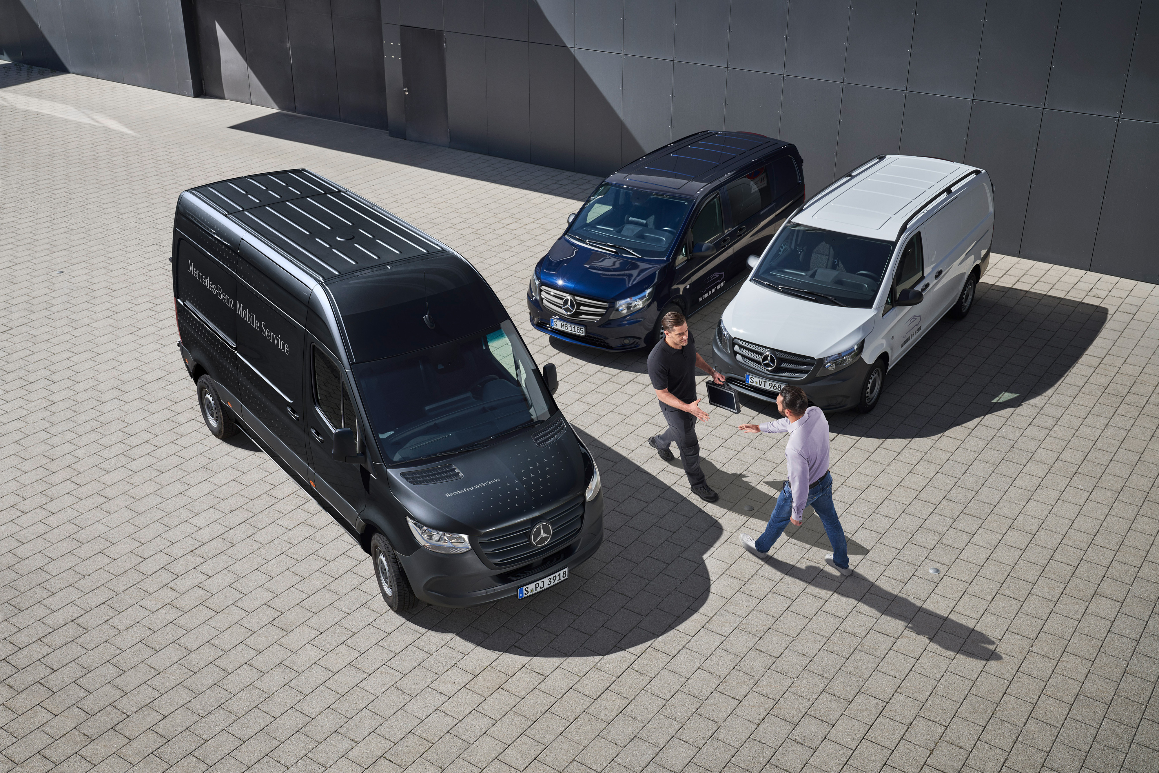 Mercedes-Benz | Aperçu des services | Service mobile Deux hommes se saluent au milieu d’utilitaires légers Mercedes-Benz.