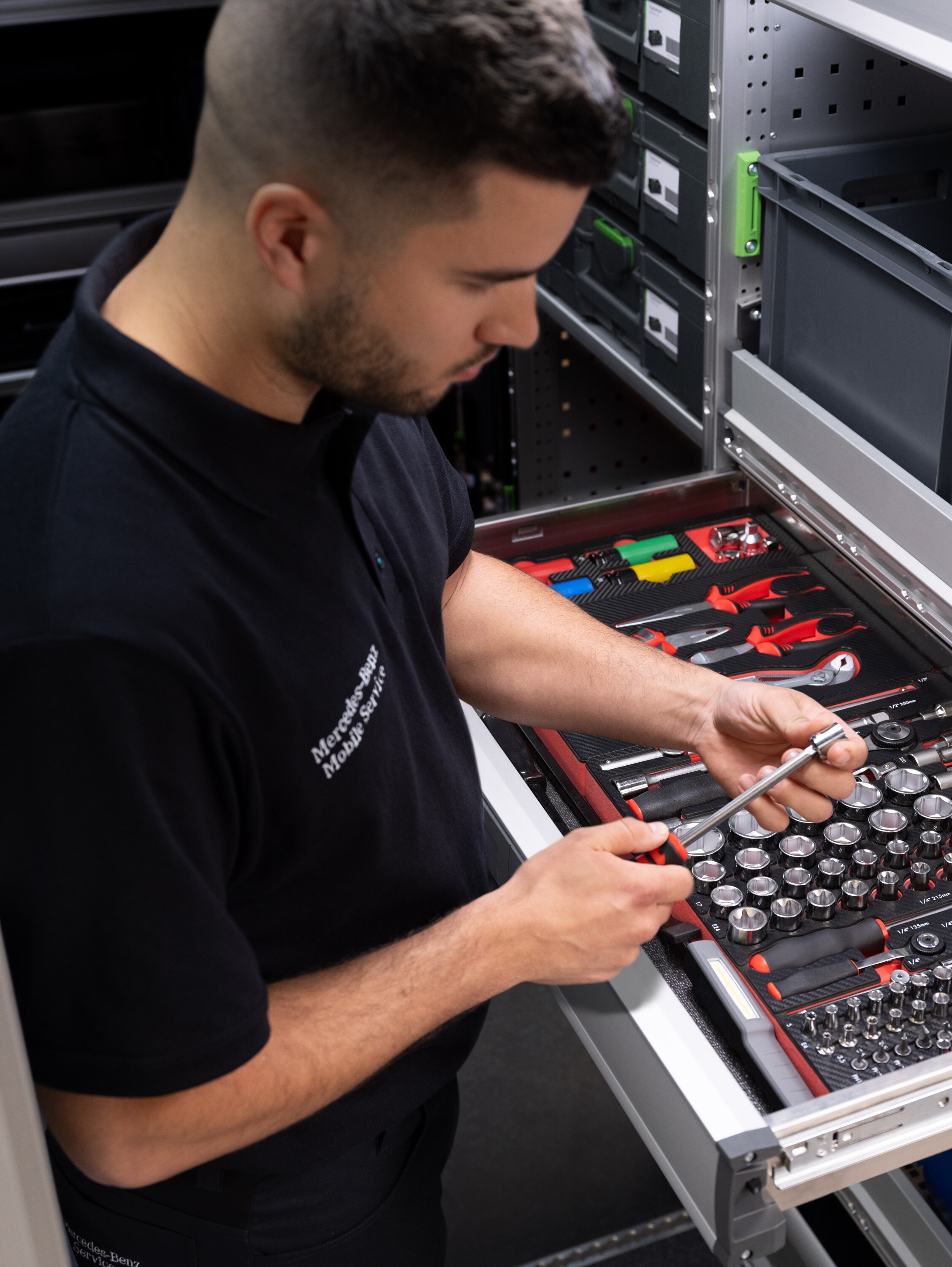 Un technicien sélectionne un article dans un tiroir rempli d'outils.