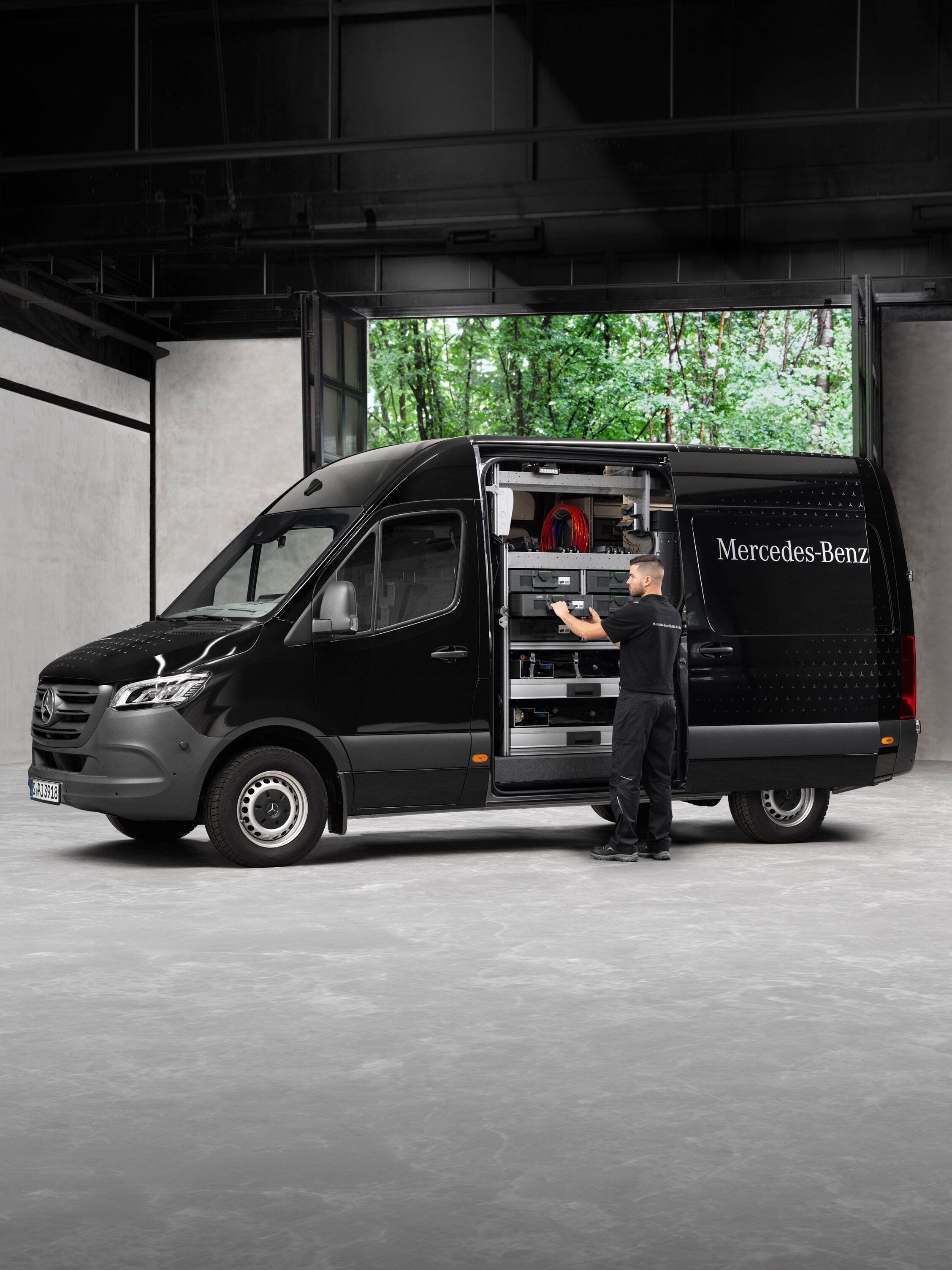Ein Techniker holt Werkzeuge aus einem schwarzen Mercedes-Benz Sprinter.